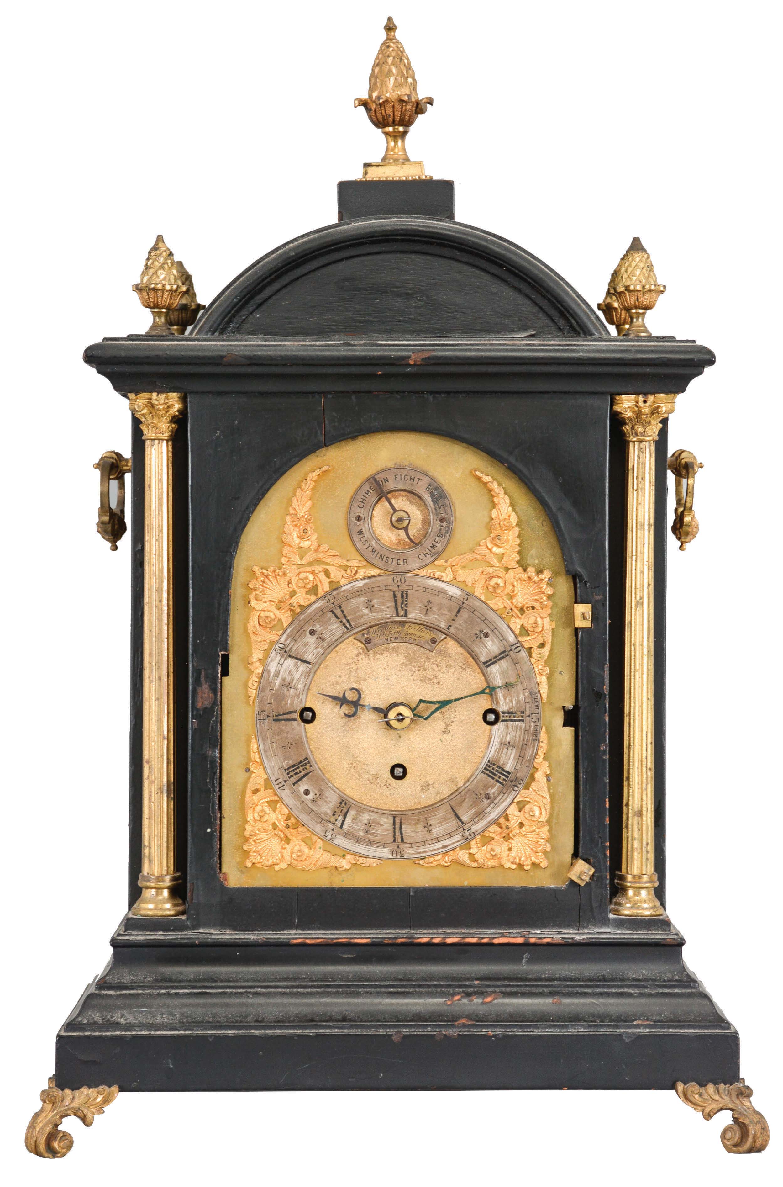 England, for Theodore B. Starr, New York, ebonized, quarter striking bracket clock, the molded base with gilt scroll feet, gilt, fluted columns supporting the cornice and dome top, and flanking the cast, foliate bezel and composite dial with Roman numeral chapter ring and strike selector in the arch, sides with pierced frets and carrying handles, top with five pineapple finials, three train fusee movement chiming on eight bells, and striking the hours on a gong — Antique Clocks Price Guide