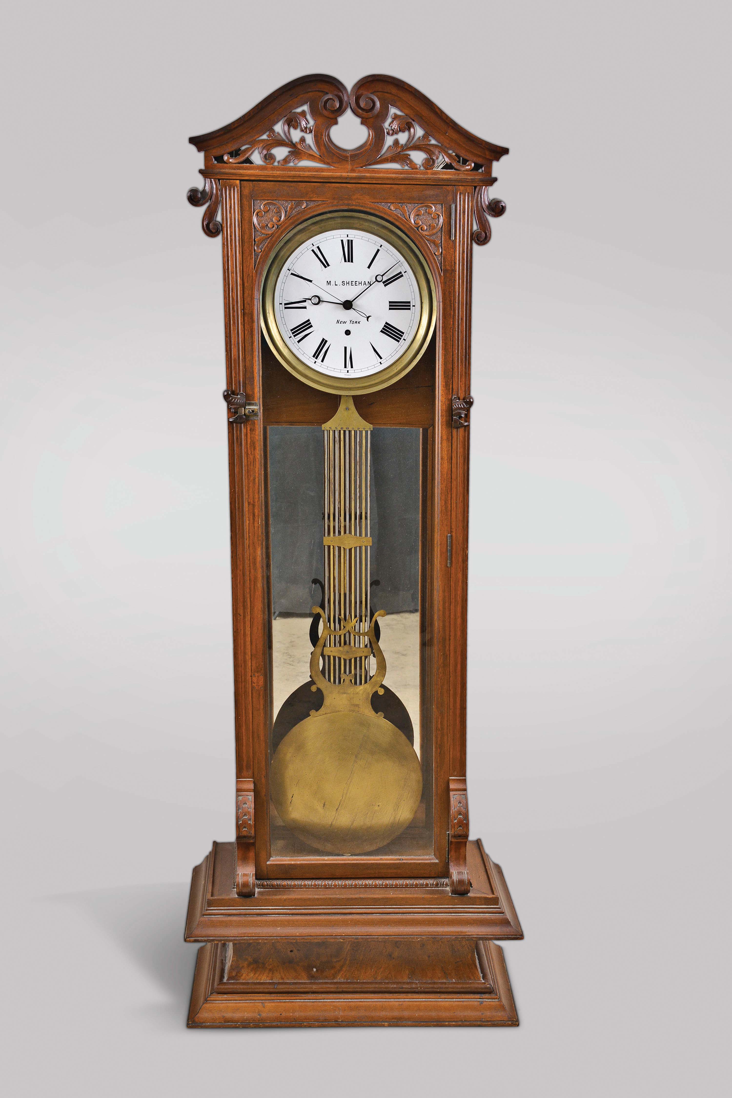 Standing Jeweler's Regulator retailed by M.L. Sheehan, New York, New York, 8 day, time only, weight driven movement with French pinwheel escapement, center seconds and gridiron lyre pendulum in a later custom built mahogany case with pierced and carved crest, white enamel dial. — Antique Clocks Price Guide