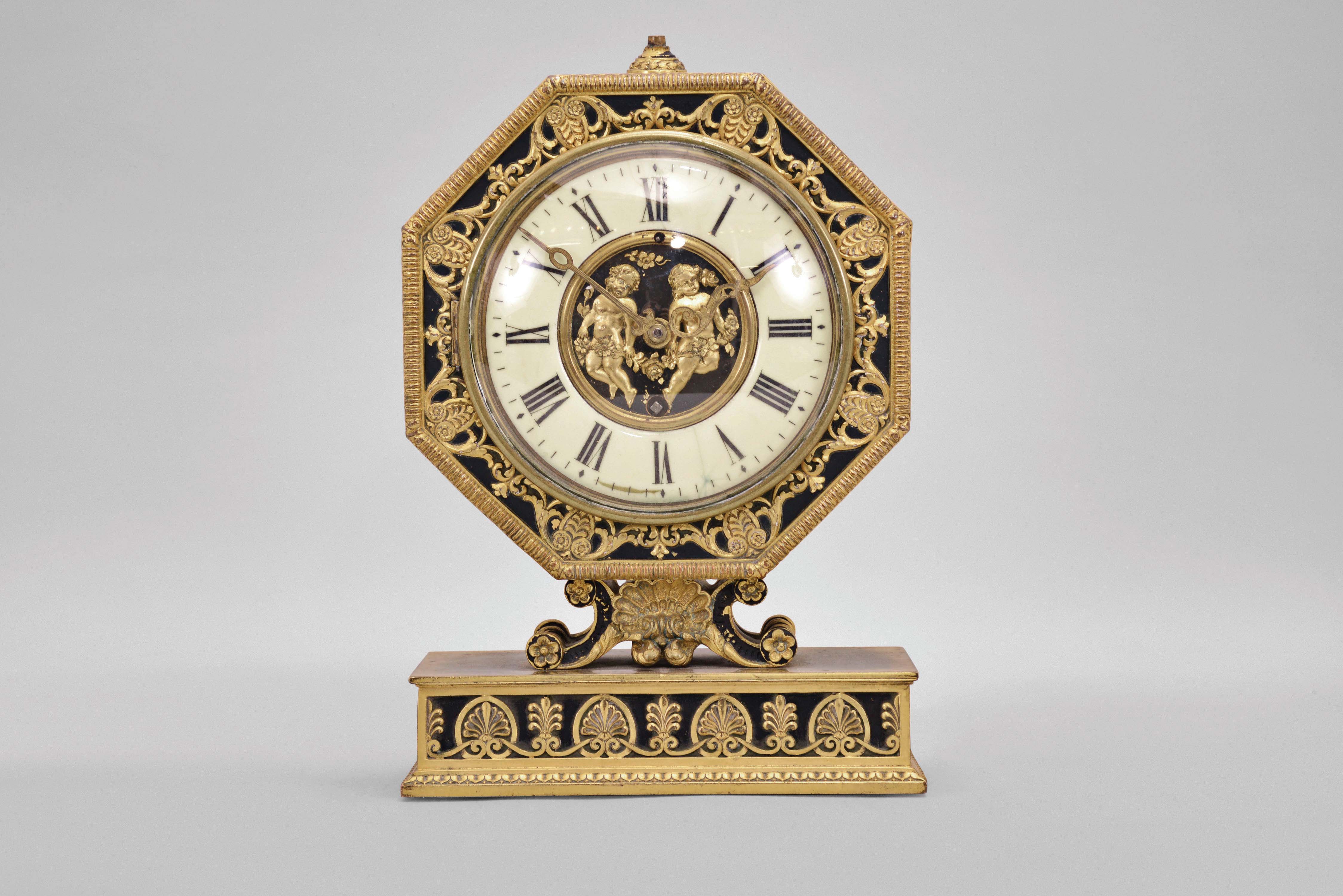 E. F. Caldwell, New York, a gilt and patinated bronze table clock, the base with leaf and dart molding, inset panels with alternating anthemion and palmette ornament, supporting a scallop shell with flanking scrolls and surmounted by the octagonal clock case, also with classical ornament, Roman numeral white enamel dial with central, gilt plaque featuring putti with garlands, gilt, engraved hands, and 8 day Chelsea timepiece movement, serial #134868 — Antique Clocks Price Guide