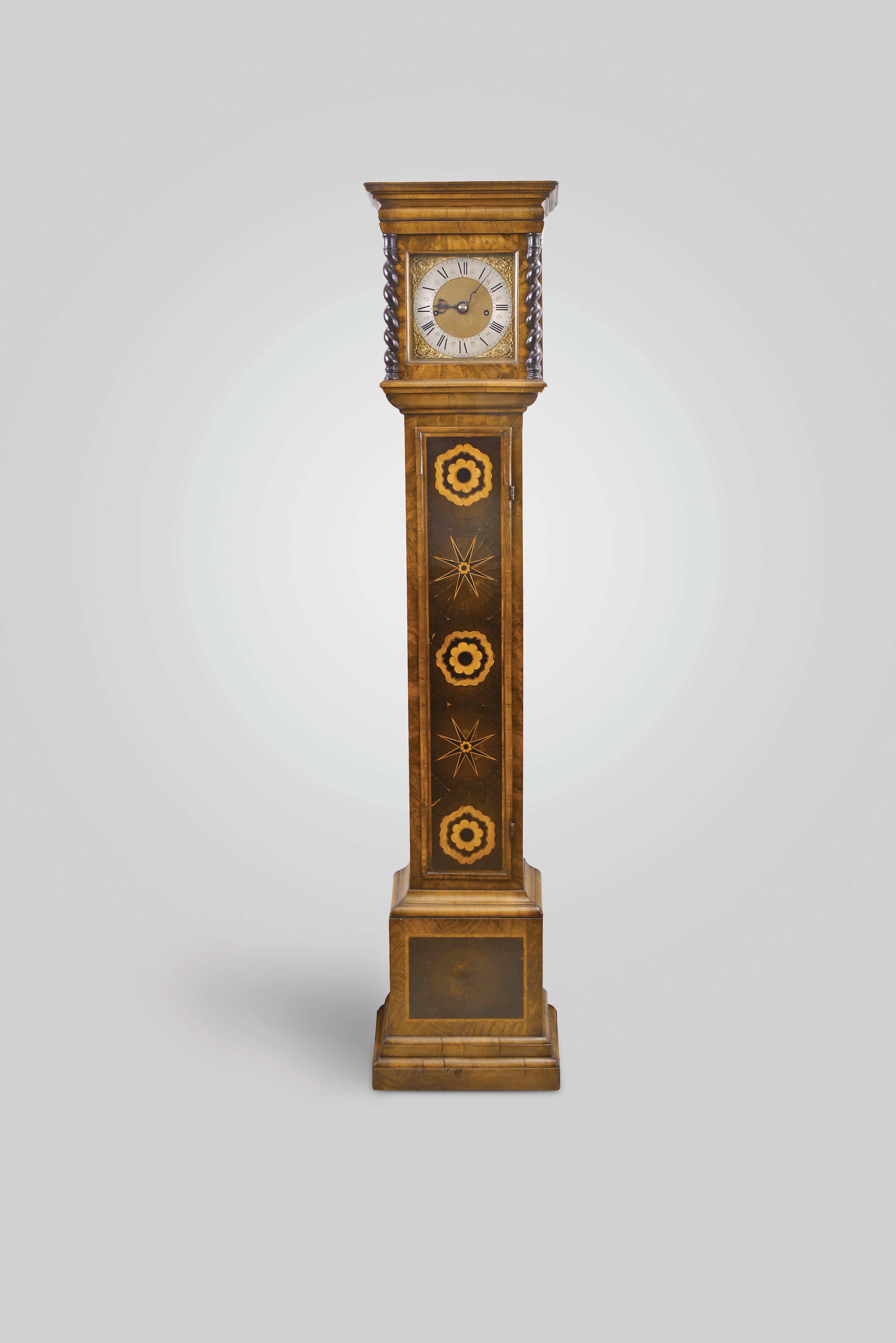 England, dwarf tall clock, 8 day, time and strike, weight driven five posted movement in an oyster wood veneered case with marquetry inlay on door and string inlay on sides of case and barley twist column flanking hood door. The brass dial has silvered chapter ring, brass corner spandrels and matted brass center with early serpentine hands. — Antique Clocks Price Guide