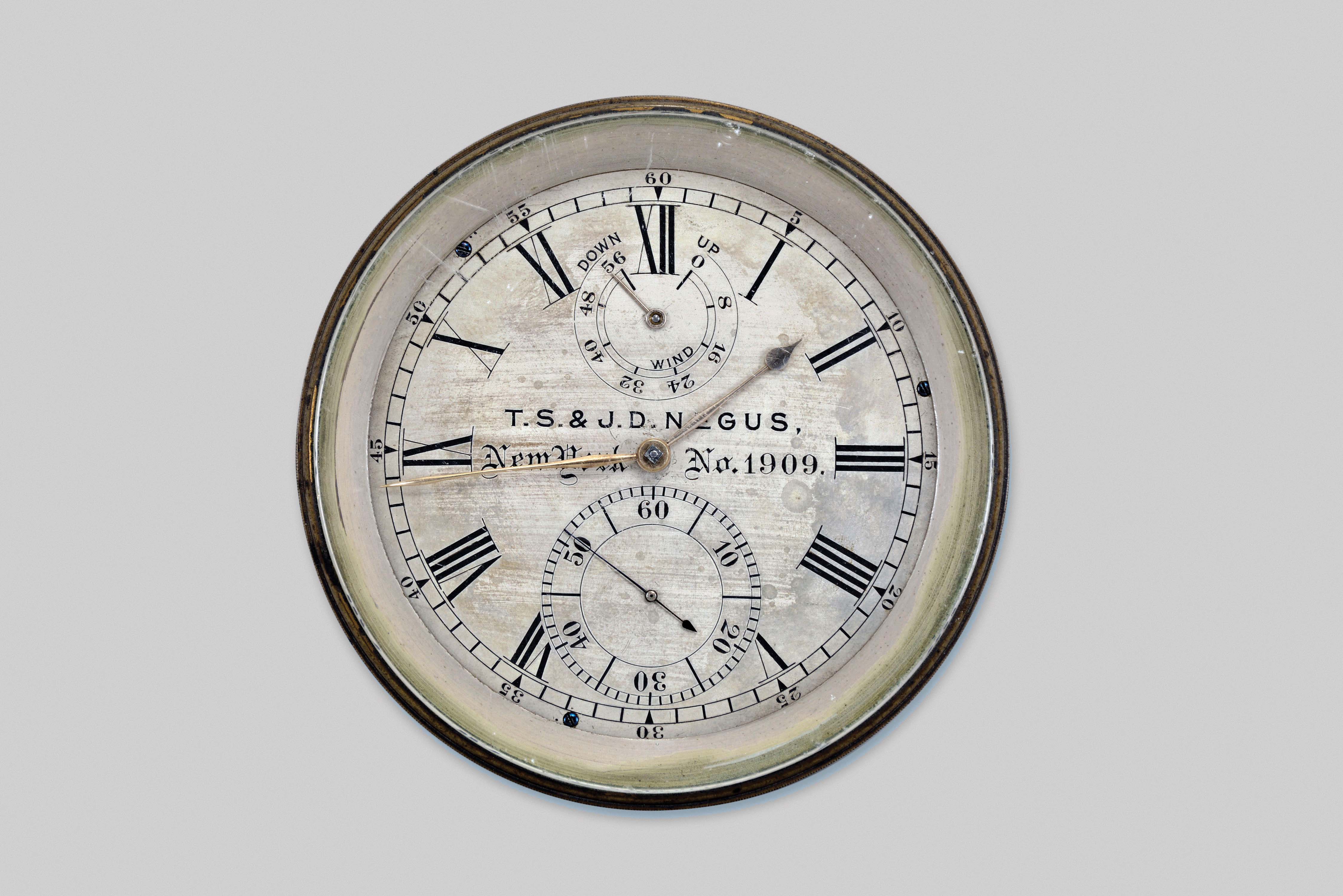 T.S. & J.D. Negus, New York, two day marine chronometer, 11 jewel fusee movement with Earnshaw's escapement, freesprung, cut bimetallic balance, diamond endstone, and blued steel helical balance spring, the bottom plate with screw holes for break circuit contact, seconds arbor with additional wheel for break circuit mechanism, Roman numeral silvered dial with wind indicator and gold spade and poker hands, contained in a brass bowl, serial #1909, lacking box — Antique Clocks Price Guide