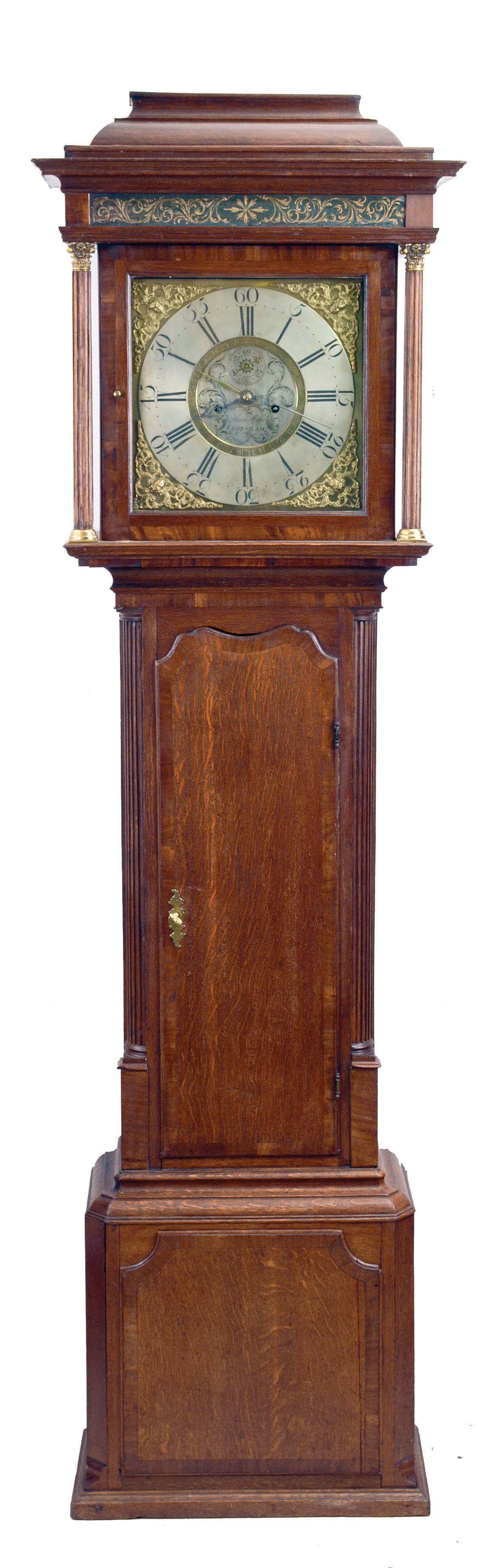 Thomas Moss, Frodsham, England, tall clock, 8 day, time and strike, weight driven movement in an oak case with mahogany banding, bell top, four full reeded Corinthian columns on the hood with painted foliate frieze above dial, reeded quarter columns flanking trunk door. The brass dial has brass corner spandrels, silvered chapter ring and silvered center boss with maker's signature and seconds bit and surrounded by brass calendar ring indicated by hand off of center arbor. — Antique Clocks Price Guide