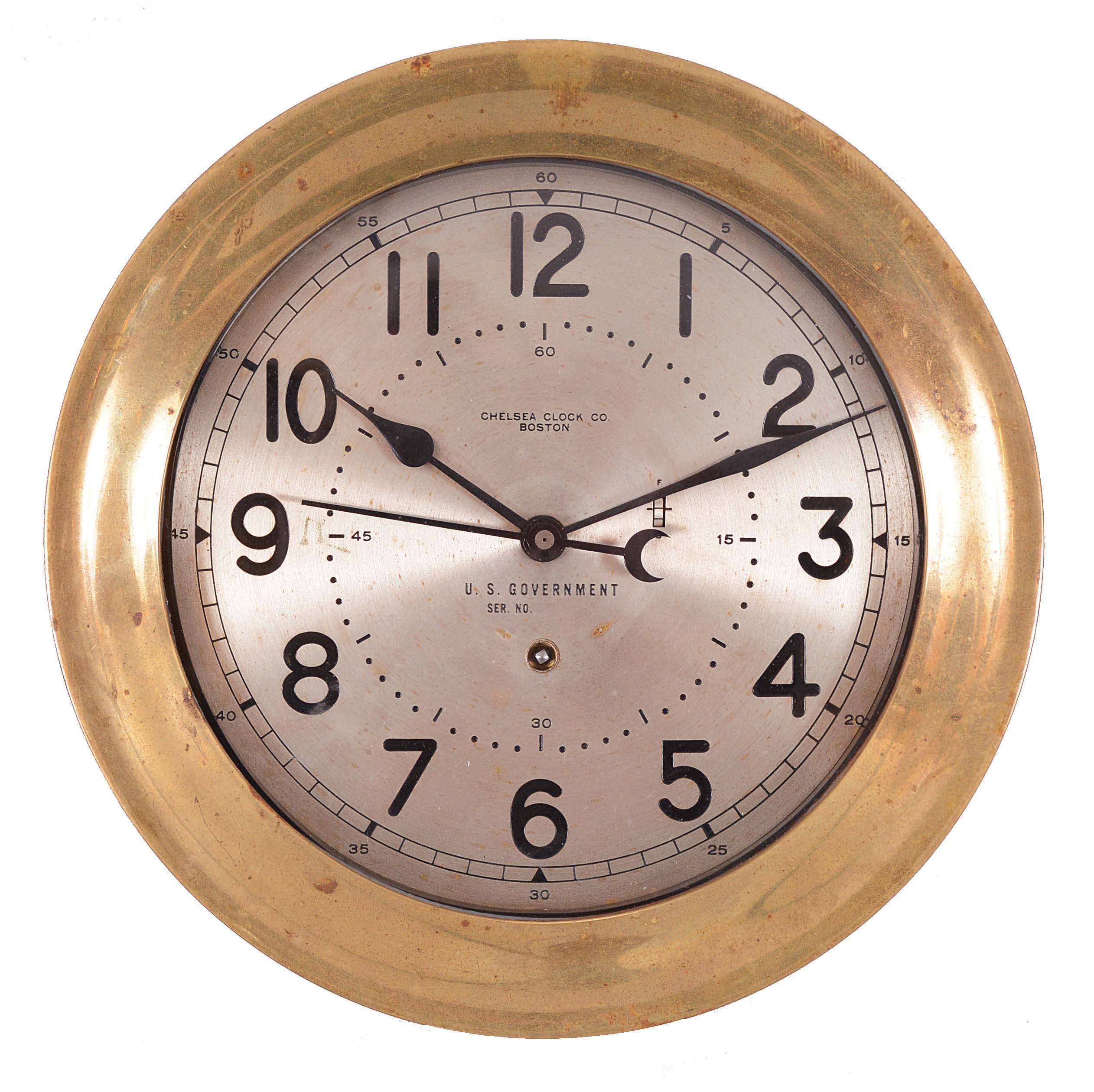 Chelsea Clock Co., Boston, Mass., "12E Deck & Engine Room Clock", 8 day, time only, spring driven movement with jeweled lever escapement and center seconds in a brass case with hinged bezel, 8.5 inch silvered dial signed by the maker and "U.S. Government" with black Arabic numerals, movement serial number 599362, c1954. — Antique Clocks Price Guide