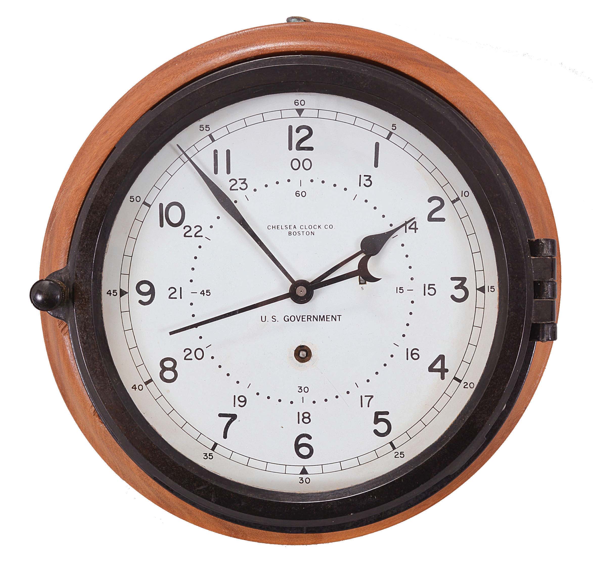 Chelsea Clock Co., Boston, Mass., "12E Deck & Engine Room Clock", 8 day, time only, spring driven movement with jeweled lever escapement and center seconds in a black phenolic case with hinged bezel, 8.5 inch white dial signed "U.S. Government" with 12 and 24 hour markers, blued steel spade hands, all mounted to a molded hardwood backer, movement serial number 871004, c1992. — Antique Clocks Price Guide