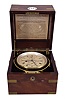 Dent, London, a good two day marine chronometer with Dent's staple balance, 11 jewel, spotted fusee movement with Earnshaw's escapement, freesprung bimetallic staple balance with blued helical balance spring and diamond endstone, Roman numeral silvered dial with wind indicator, blued steel spade and poker hands, with lacquered brass bowl and gimbals, and contained in a three tier mahogany and mahogany veneer box with brass furniture, the front with round plaque marked "Dent 3043", the inside of the lid with E. dent & Co. label