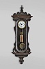 Austria, a miniature weight driven Vienna timepiece, rosewood grained softwood case with serpentine door, deeply molded bottom bracket with turned drop, ogee molded top and bottom, and removable scrolled crest with turned finial, Roman numeral white enamel dial, pierced, blued steel Vienna style hands, 30 hour, weight driven timepiece movement with recoil escapement and silk thread suspension, 5 spoke pulley, and pendulum with brass bob and steel rod