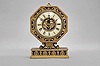 E. F. Caldwell, New York, a gilt and patinated bronze table clock, the base with leaf and dart molding, inset panels with alternating anthemion and palmette ornament, supporting a scallop shell with flanking scrolls and surmounted by the octagonal clock case, also with classical ornament, Roman numeral white enamel dial with central, gilt plaque featuring putti with garlands, gilt, engraved hands, and 8 day Chelsea timepiece movement, serial #134868