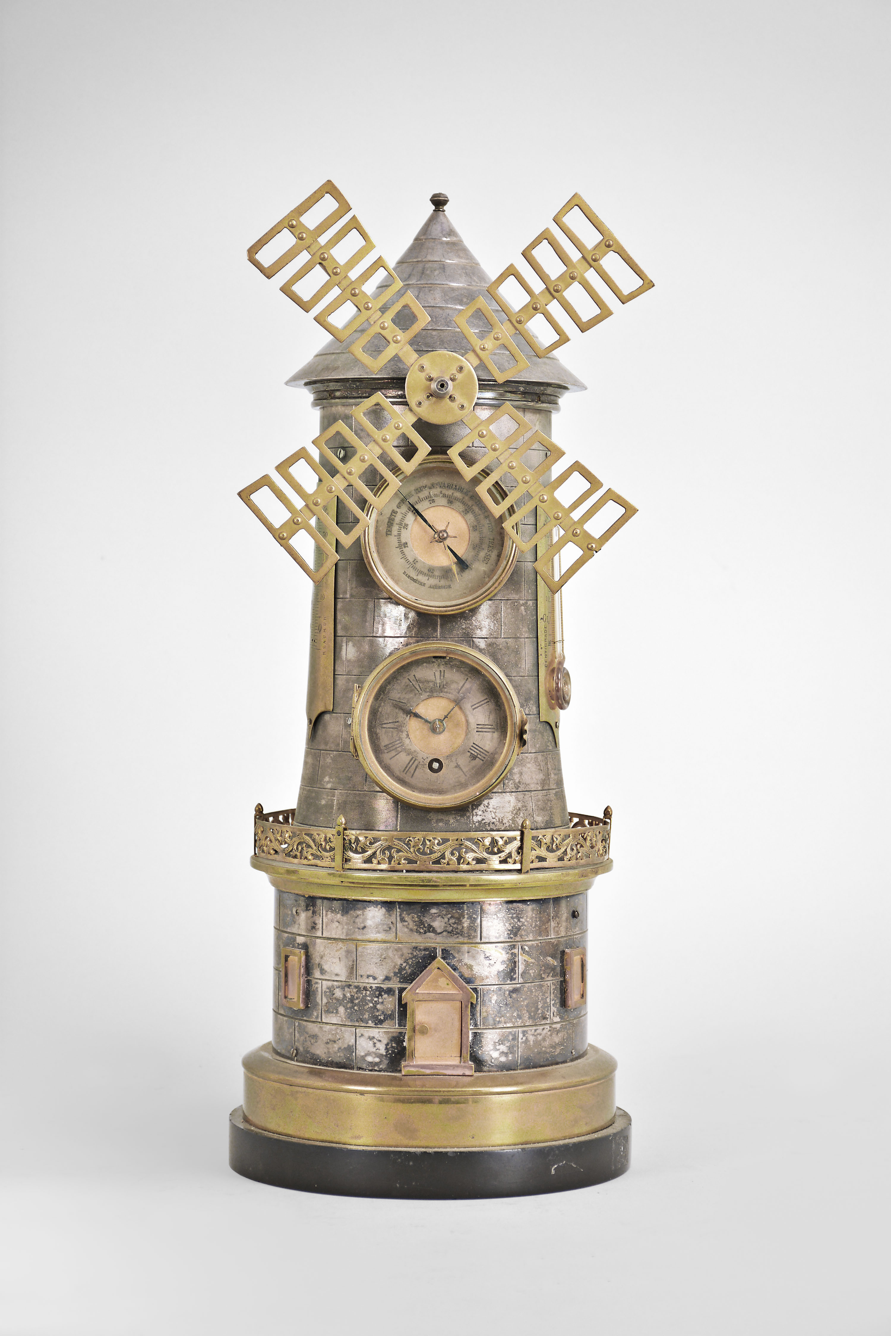 France, industrial series windmill, 8 day timepiece and barometer, spring driven movement in a gilt and silvered brass case with black slate base, mid section with pierced railing, lower section with two simulated windows flanking a door, the door opening to access the windmill movement winding arbor, front with clock and barometer dials, the sides with Fahrenheit and Celsius thermometers. — Antique Clocks Price Guide