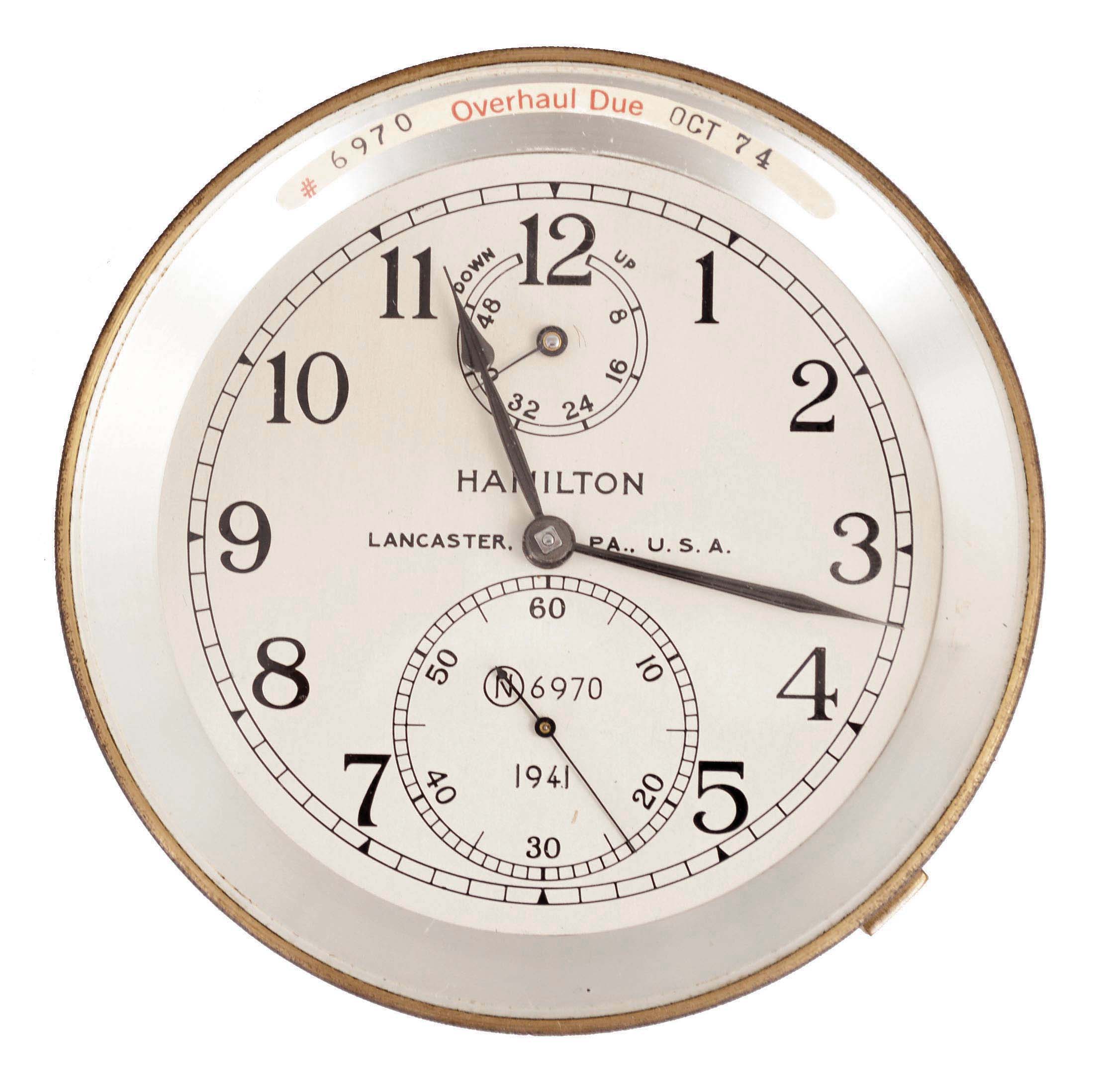 Hamilton Watch Co., Lancaster, Penn., model 21 marine chronometer with bowl, 14 jewel, key wind and set, straight line damascened nickel plate movement with spring detent escapement and chronometer balance with helical balance spring, Arabic numeral silvered metal dial with wind indicator, black painted steel spade and poker hands, serial #2E6970, together with its padded aluminum shipping container — Antique Clocks Price Guide