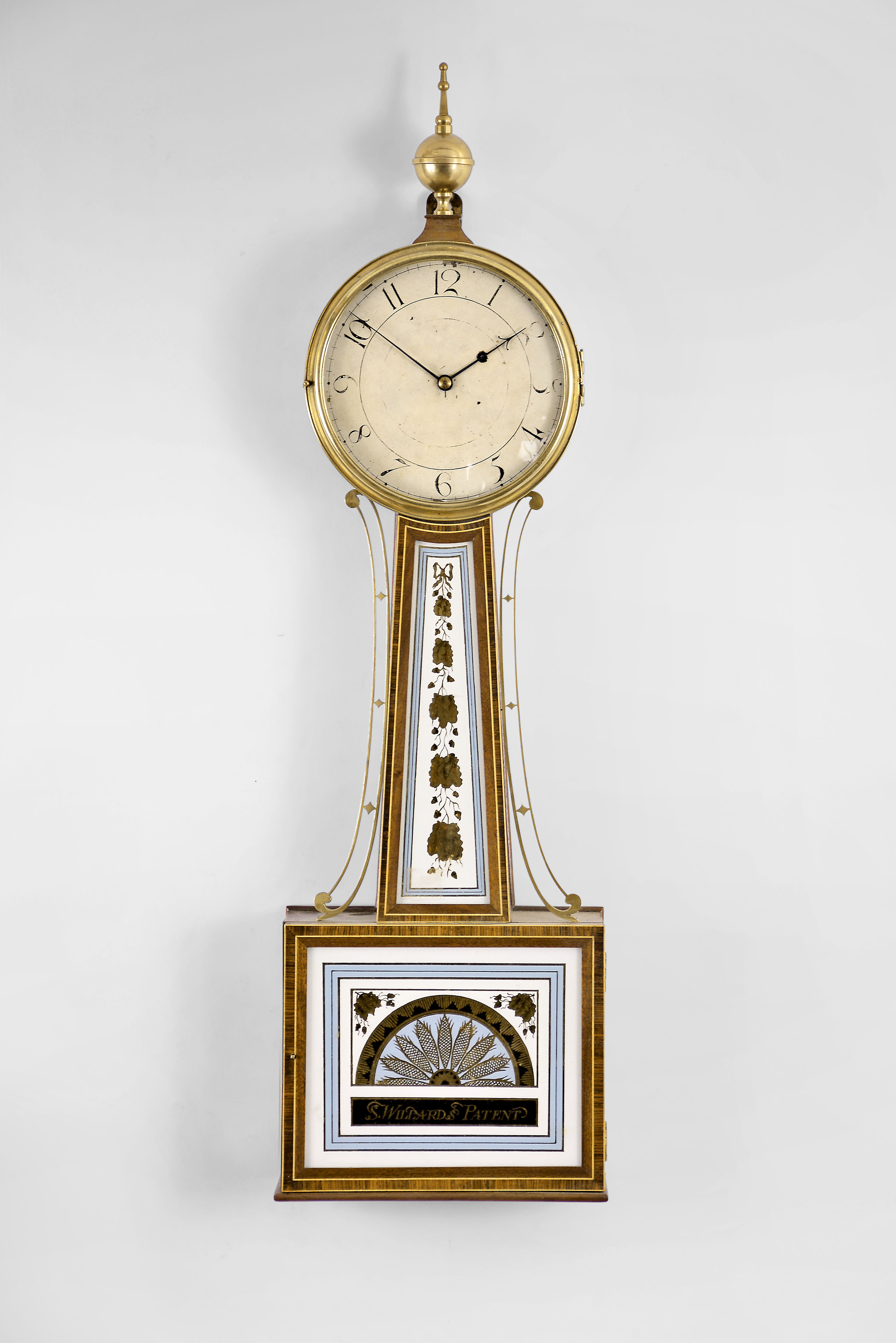 Willard school banjo wall clock, 8 day, time only, weight driven movement with T-bridge suspension in an inlaid mahogany case with reverse painted throat and lower tablets and a painted metal dial — Antique Clocks Price Guide