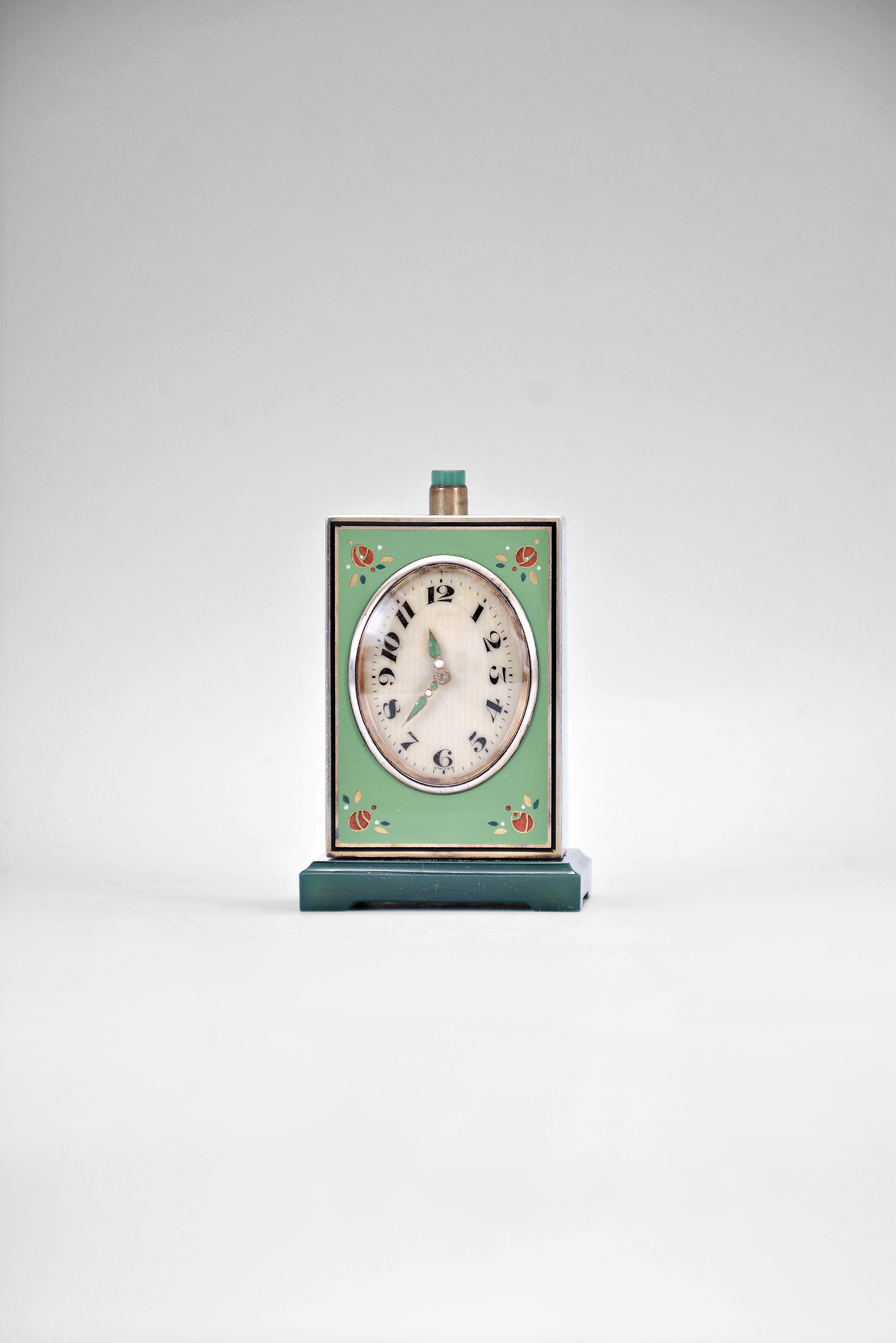 Mathey Tissot and Co., Switzerland, an enamelled, miniature, minute repeating travel or desk clock with leather bound box, the silver gilt case with black bordered, green enamel panels, with polychrome enamel and gilt ornament, and resting on a molded, green jade base, arabic numeral oval dial with enamelled silver gilt hands, 15 jewel, key wound and set nickel movement with lever platform and cut bimetallic balance, the repeating activated through a jade and silver gilt button at case top, contained in its original gilt stamped, green leather bound, silk lined protective box. — Antique Clocks Price Guide