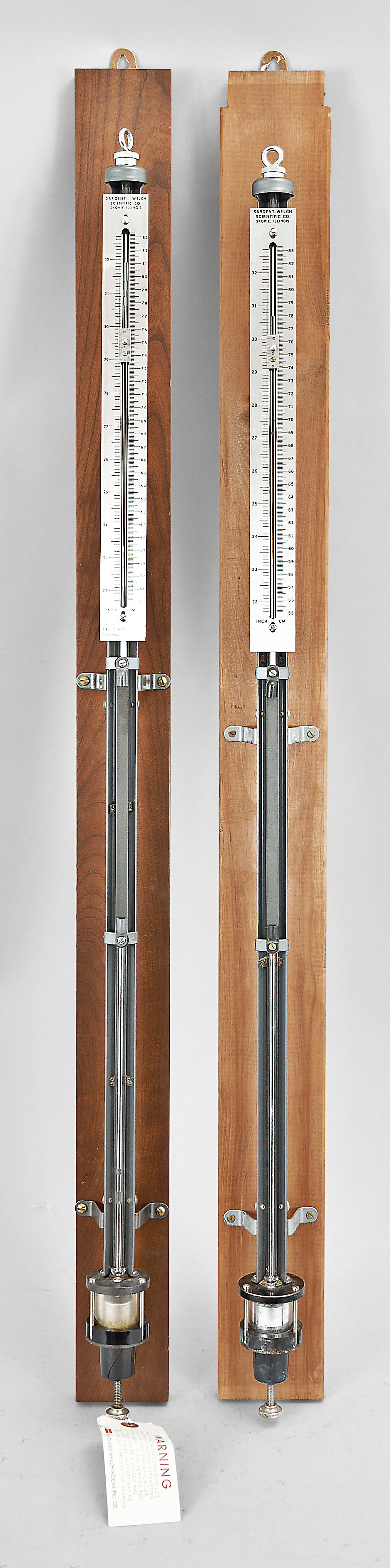 Barometers- 2 (Two): Sargent-Welch Scientific Co., Skokie, Illinois, "U.S. Weather Bureau Type" Fortin-style mercurial barometers, polished nickel-silver engine divided scales showing both inch and centimeters with vernier plates, thumbscrew adjustment below cistern for zeroing, fixed to wood backboards for wall mounting. — Antique Clocks Price Guide