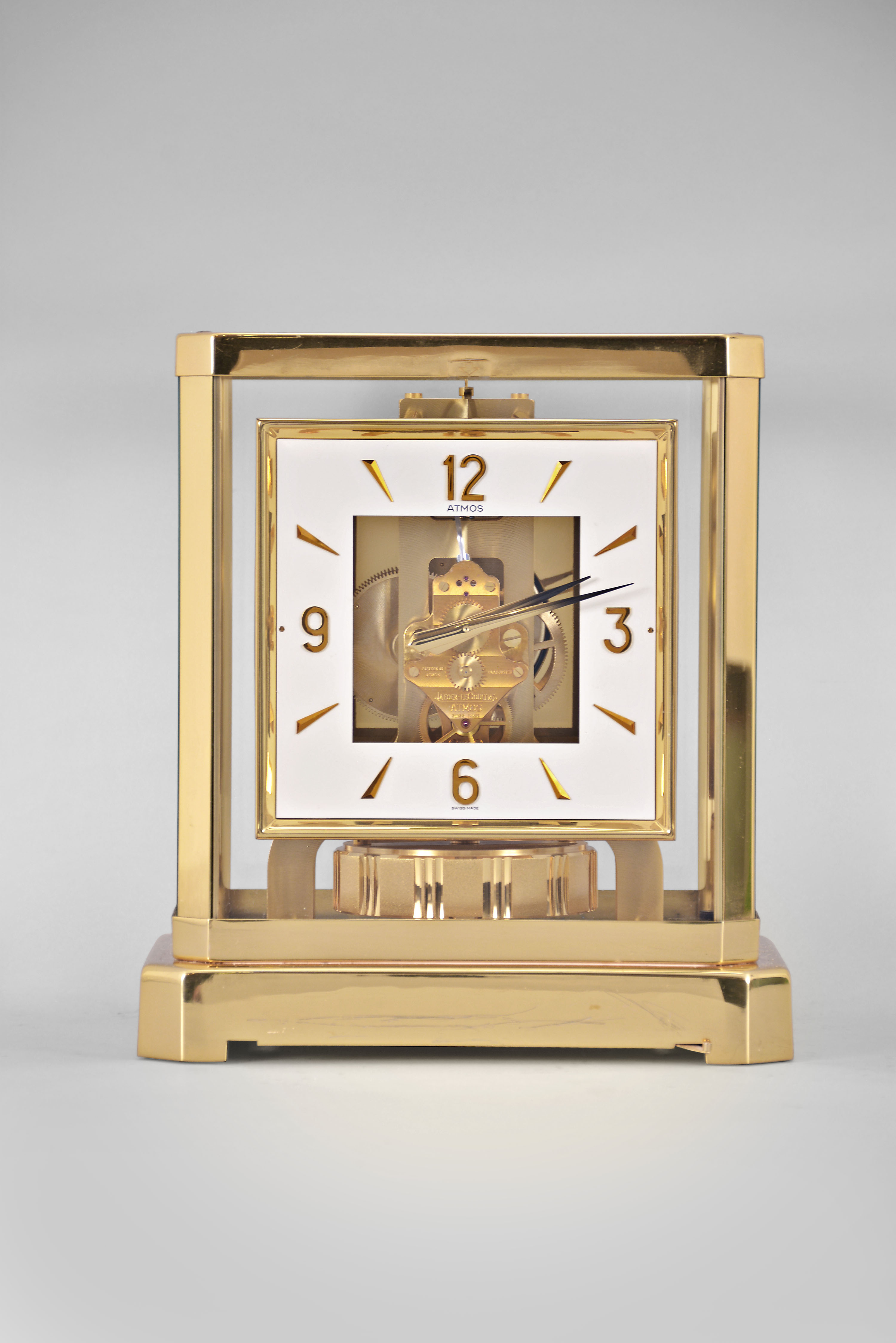 Jaeger-LeCoultre, Switzerland, "Atmos" clock, 15 jewel movement, gilt torsion pendulum, square white painted dial with applied gilt Arabic numerals and arrow markers, gilt hands all contained in a glazed rectangular case with removable front panel, serial #467632 — Antique Clocks Price Guide