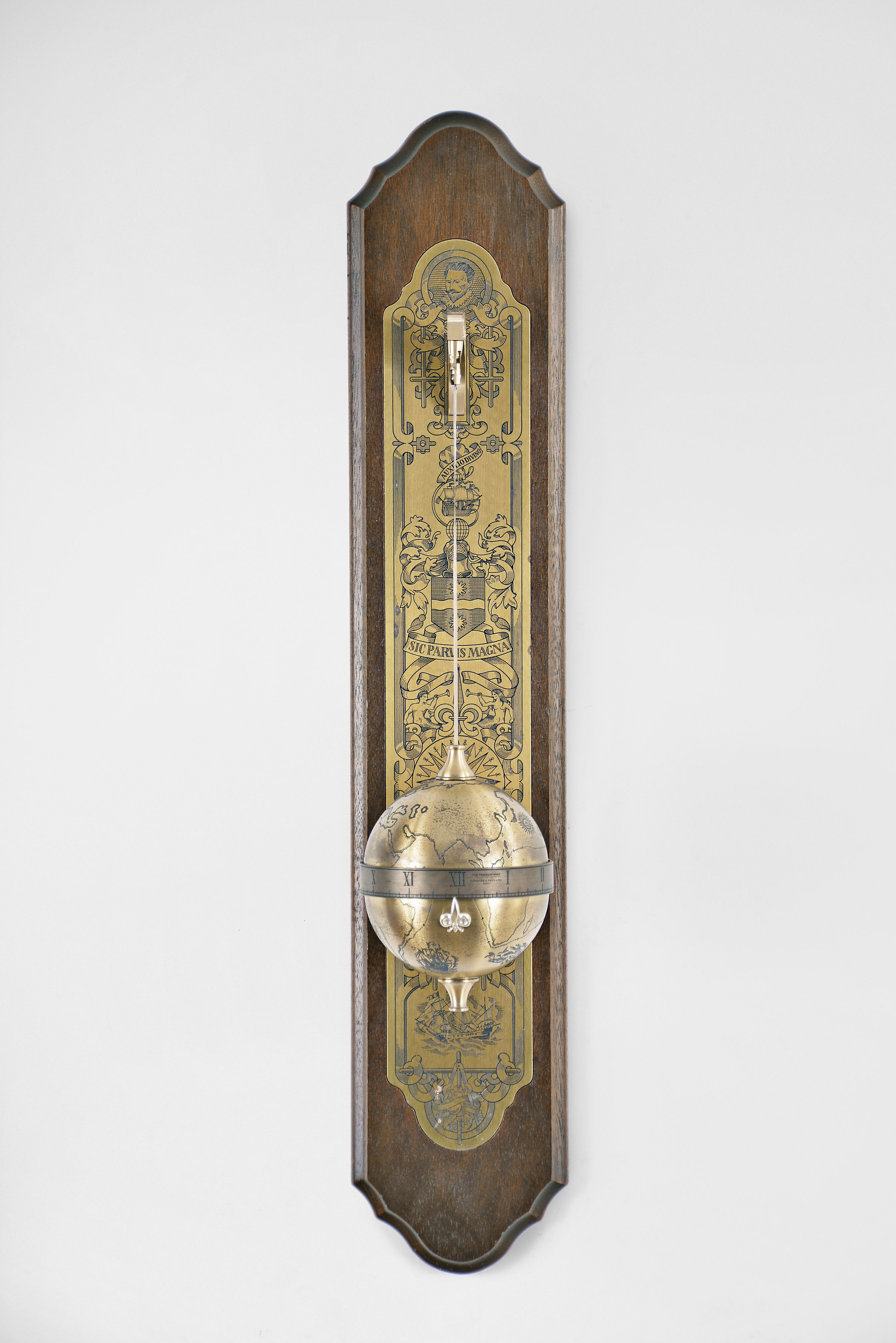 Thwaites & Reed Ltd., England for The Franklin Mint, "Sir Francis Drake Falling Ball Clock", 8 day, time only, weight driven movement with annular time display in an engraved spherical case suspended from a cast brass bracket mounted to a wood back board with engraved brass plaque. — Antique Clocks Price Guide