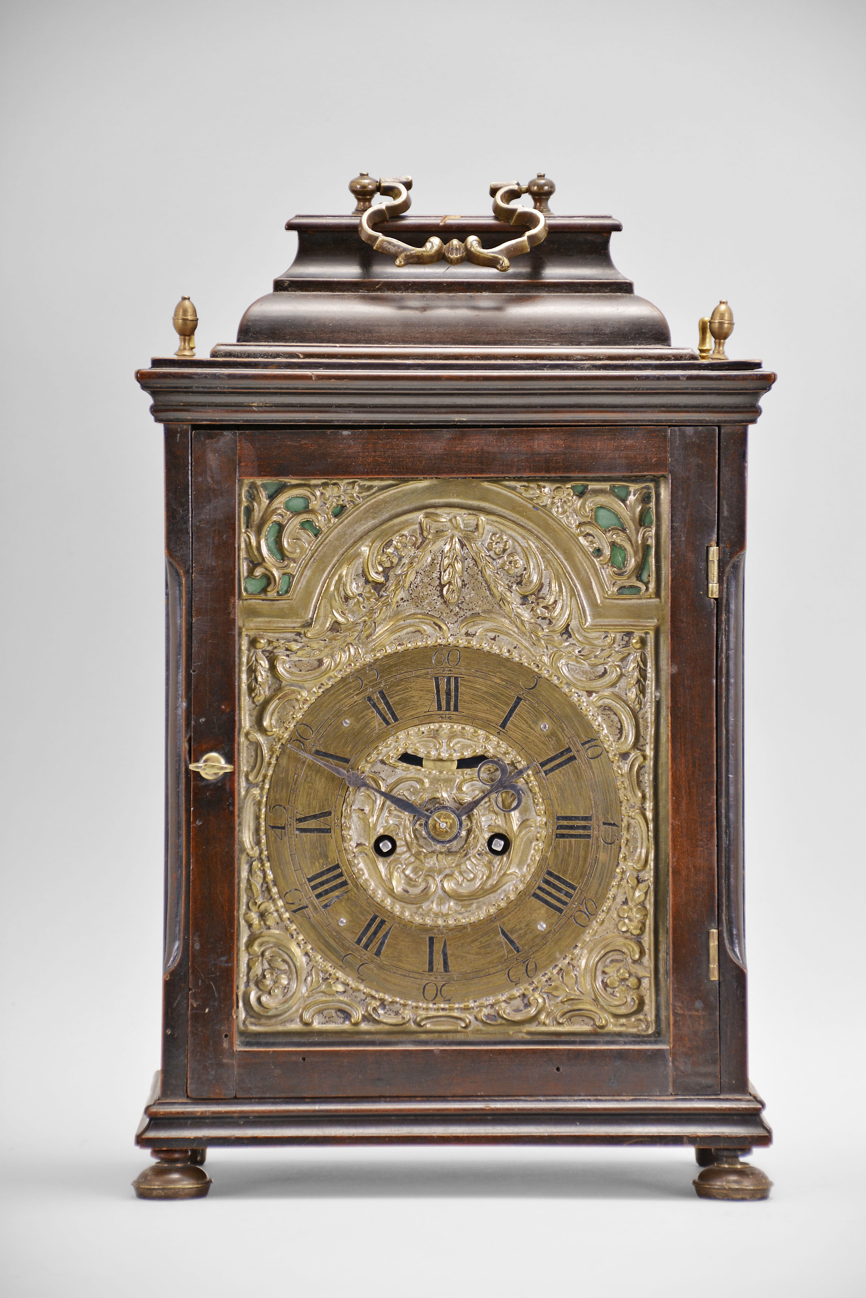 Austria, a late 18th century, repeating bracket clock with mock pendulum, ebonized hardwood case on compressed, silvered ball feet, plain rectangular door allowing a veiw of the decorative dial, molded top with brass finials and caddy top with brass handle, case sides with tombstone arch windows, and back also with rectangular, glazed door, silvered repousse dial with C scrolls, flowers, and bowknot with laurel festoon, the upper corners pierced, and with green paper backing, brass roman numeral chapter ring with arabic five minute markers, blued steel beetle and poker hands, 30- 60 hour brass movement with crown wheel escapement, rack striking, and repeating the last hour on demand — Antique Clocks Price Guide