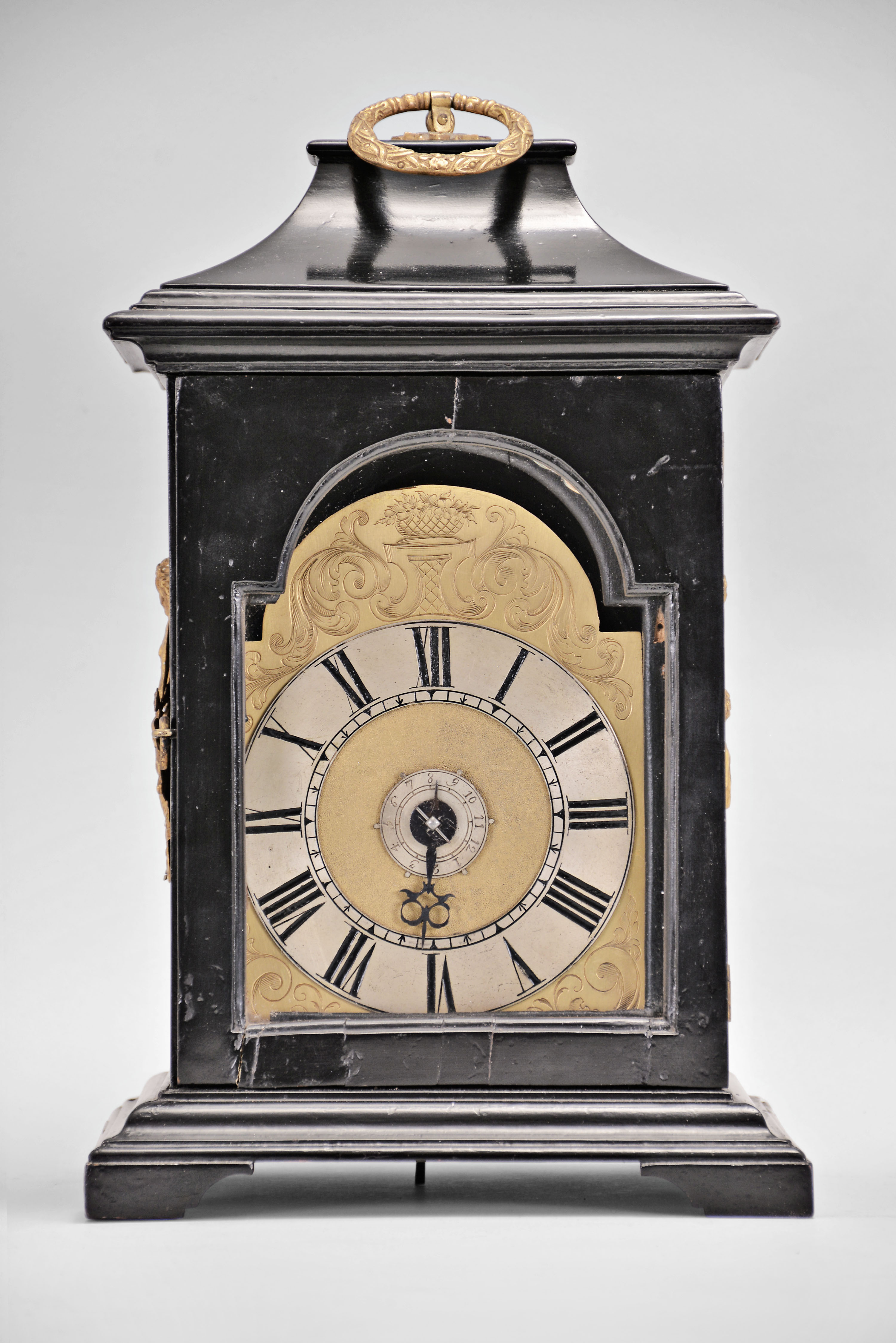 Austria, small bracket clock, 30 hour, time and alarm, round spring driven movement with verge escapement in an ebonized wood case with ogee molded base and pagoda top with gilt carrying handle, case sides with figural gilt mounts, gilt shield-shaped dial with engraving, matted center, and Roman numeral applied silvered chapter ring, silvered alarm set ring, and a single blued steel hand. — Antique Clocks Price Guide