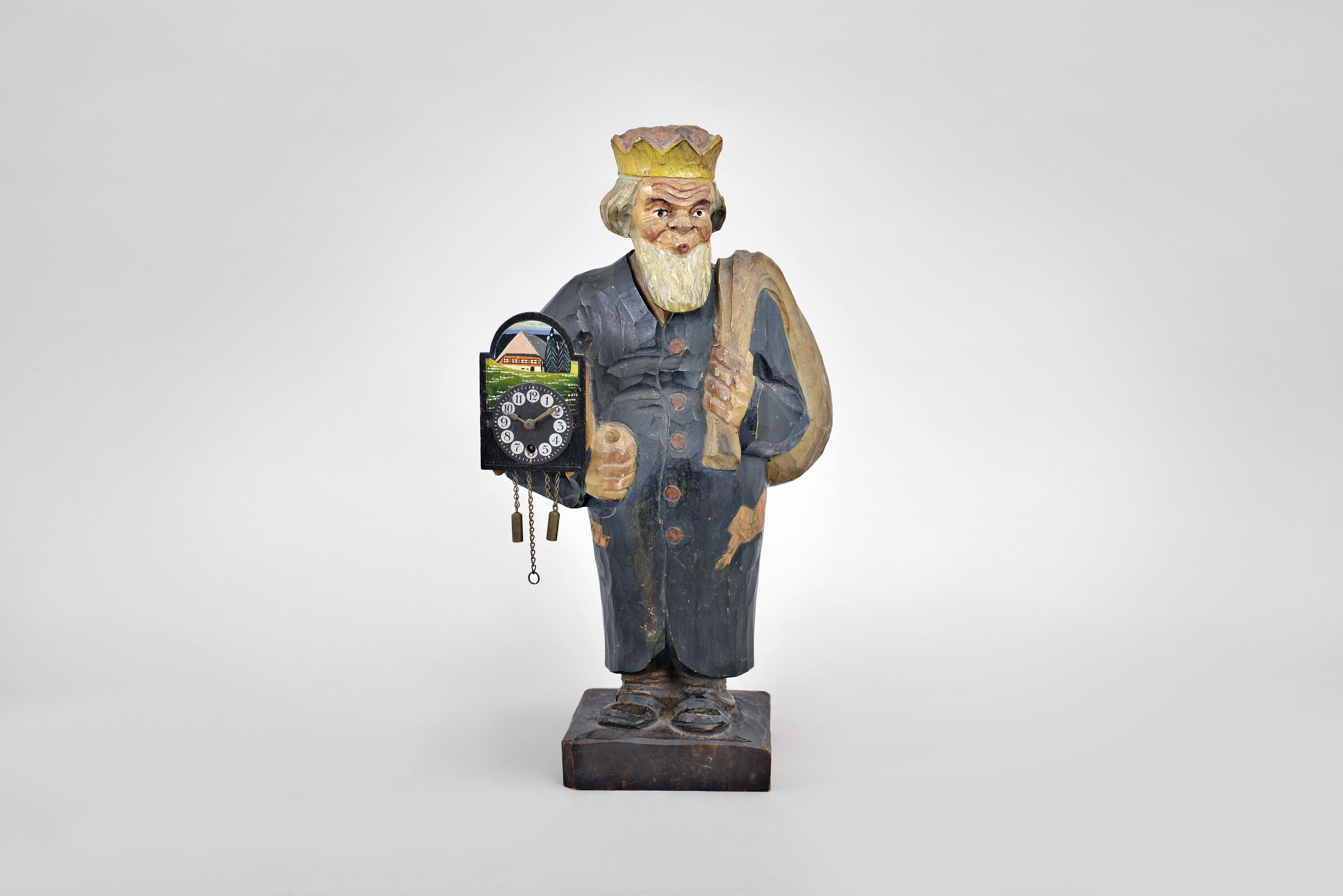 Karl Griesbaum, Triberg, Germany, "Father Christmas" whistling figure, spring driven brass movement driving air bellows, a slide whistle, and head motion, all enclosed in hand carved wooden figure depicting a bearded man carrying a sack over his shoulder, a German wall clock under his other arm, with packages and an elf in the pockets of his long coat. — Antique Clocks Price Guide