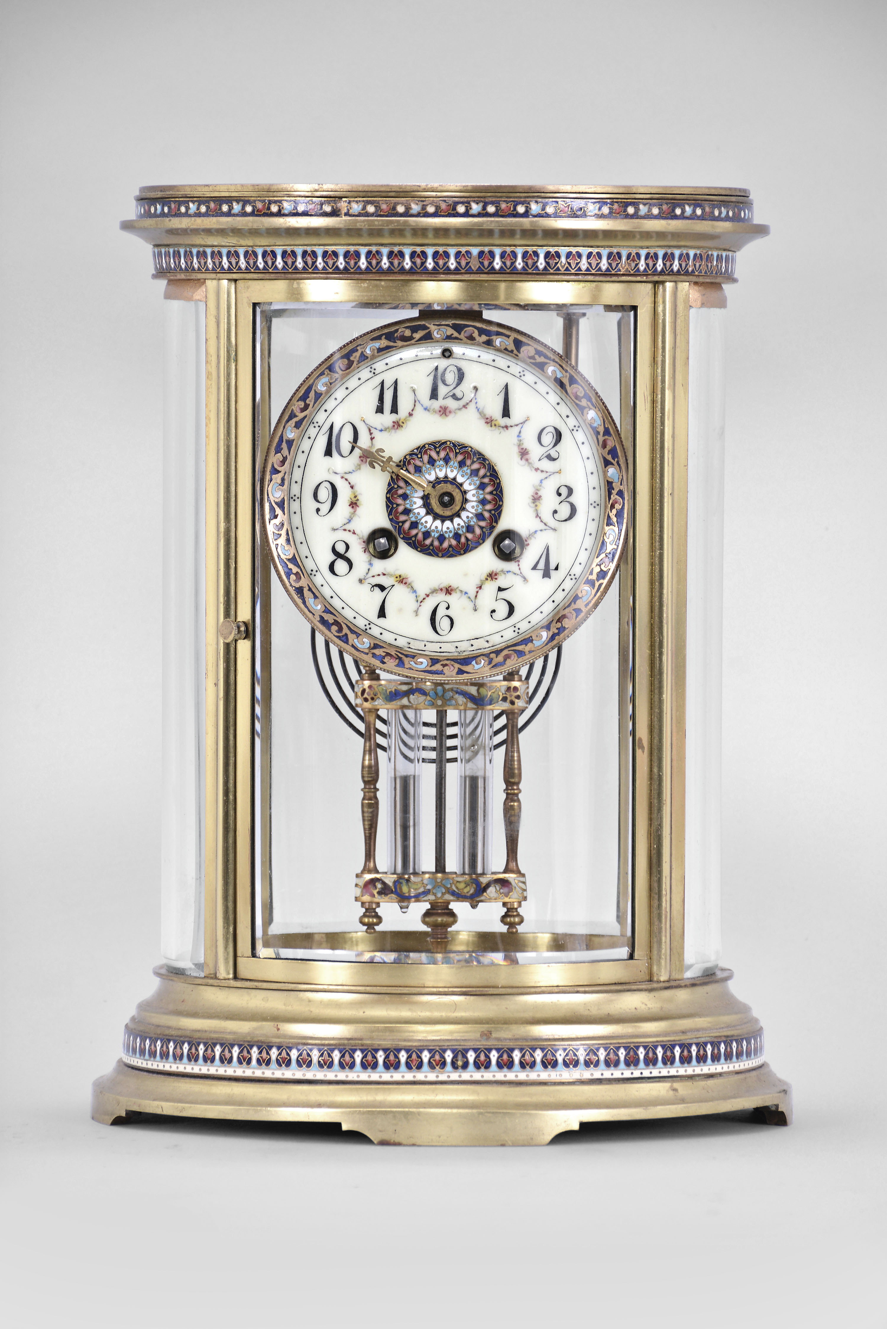 S. Marti & Cie, Paris, France, oval crystal regulator, 8 day, time and strike, spring driven pendule de Paris movement in a gilt brass case with four curved beveled glasses, cloisonne trim in bands around the case top and bottom, dial, and on the frame of the compensating pendulum, cream colored enamel dial with Arabic numerals, gilt hands, and double-vial pendulum. — Antique Clocks Price Guide