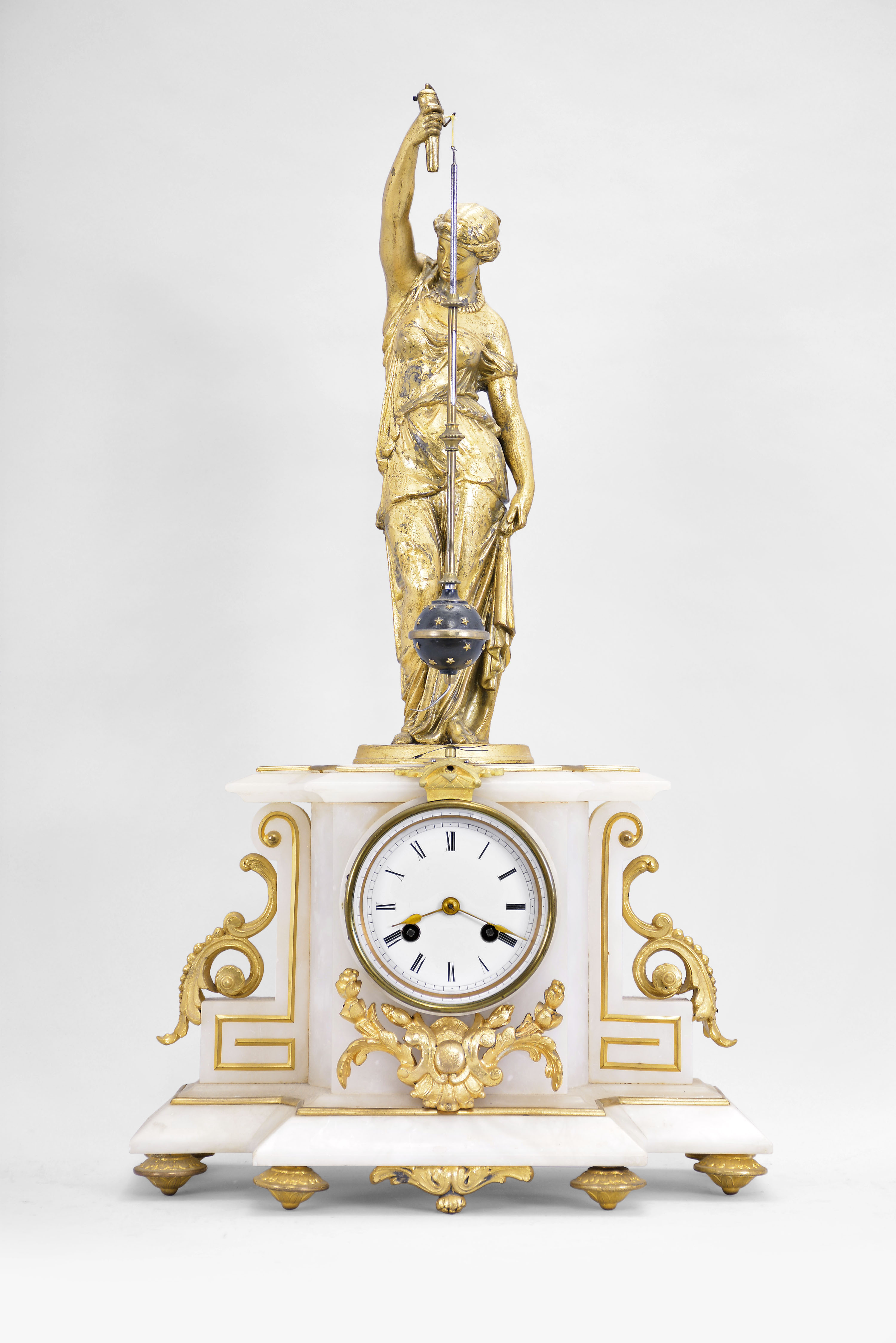 Japy Fils, Paris, France, figural mystery clock, 8 day, time and strike, spring driven movement with conical pendulum in a white alabaster case on cast feet with applied gilt ornaments, surmounted by a gilt female figure holding the pendulum aloft, Roman numeral white enamel dial, and gilt spade hands. — Antique Clocks Price Guide