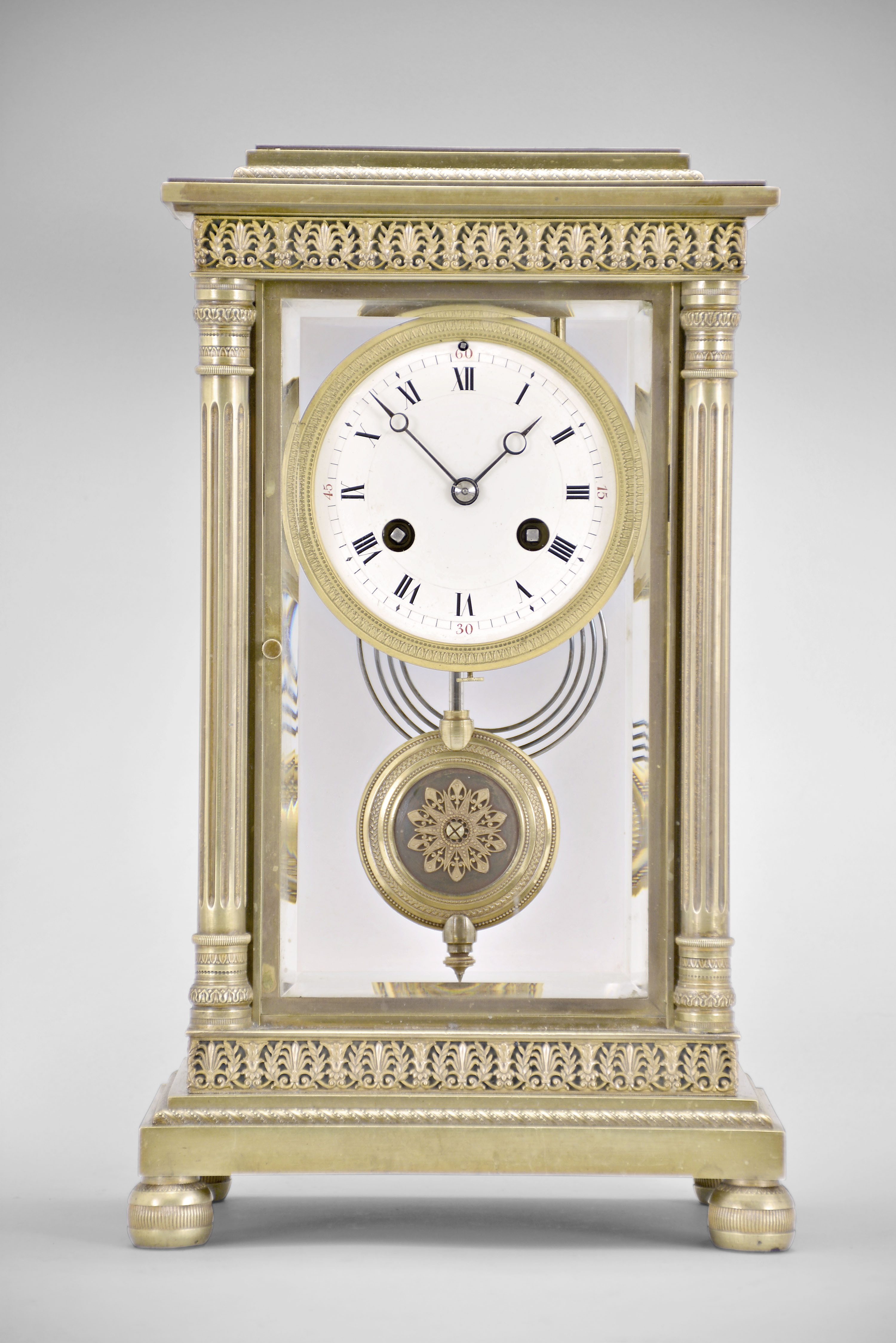 Vincenti & Cie, Paris, France, crystal regulator, 8 day, time and strike, spring driven pendule de Paris movement in a glazed brass case on cast bun feet supporting fluted columns on the front corners and pilasters on the back corners, stepped and molded base and top with repeating palmette and laurel fretwork, matching pendulum, Roman numeral white enamel dial with red Arabic numerals at the quarters, and blued steel Breguet style hands. — Antique Clocks Price Guide