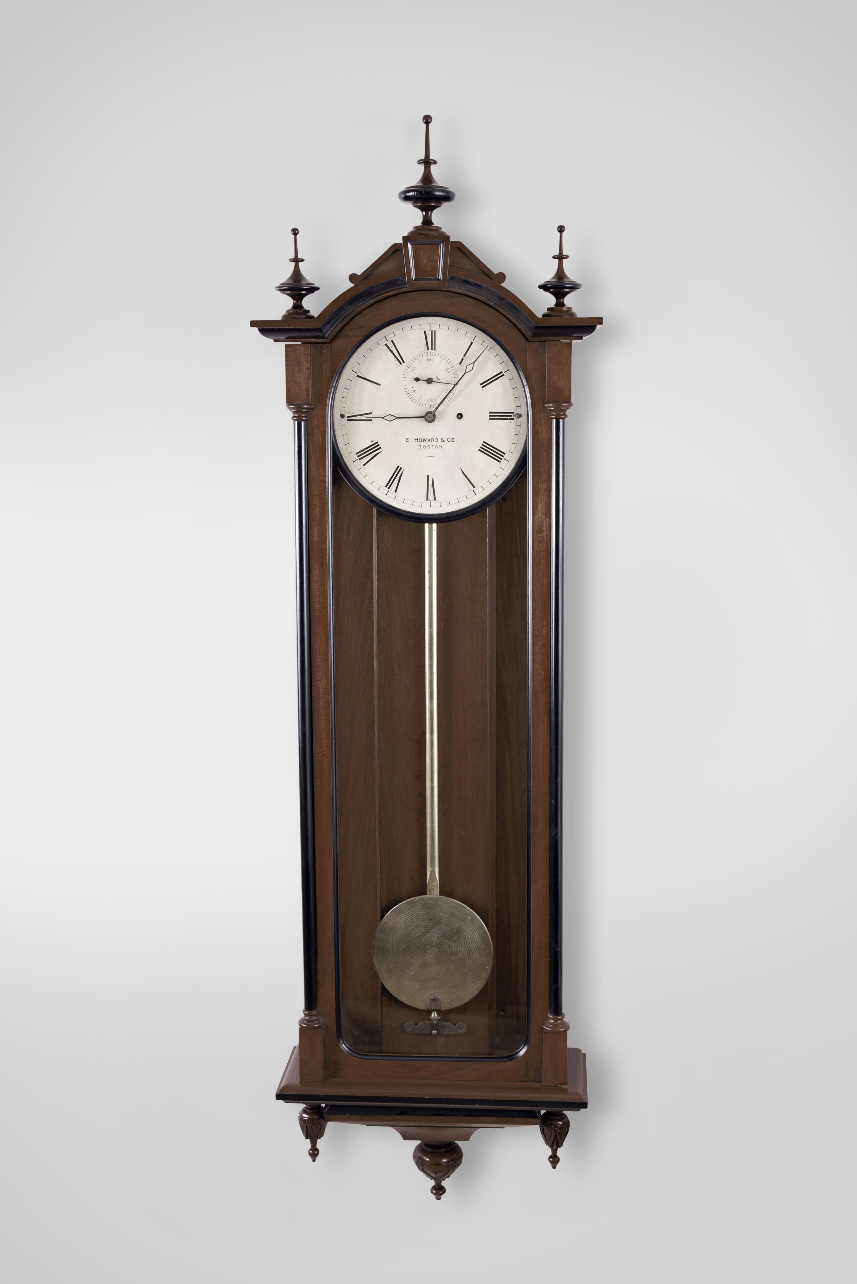 E. Howard & Co., Boston, Mass., "No. 71 Regulator" wall clock, 8 day, time only, weight driven movement with deadbeat escapement in a walnut case with ebonized trim, gilded wooden pendulum rod, damascened pendulum bob, painted metal dial and seconds bit — Antique Clocks Price Guide