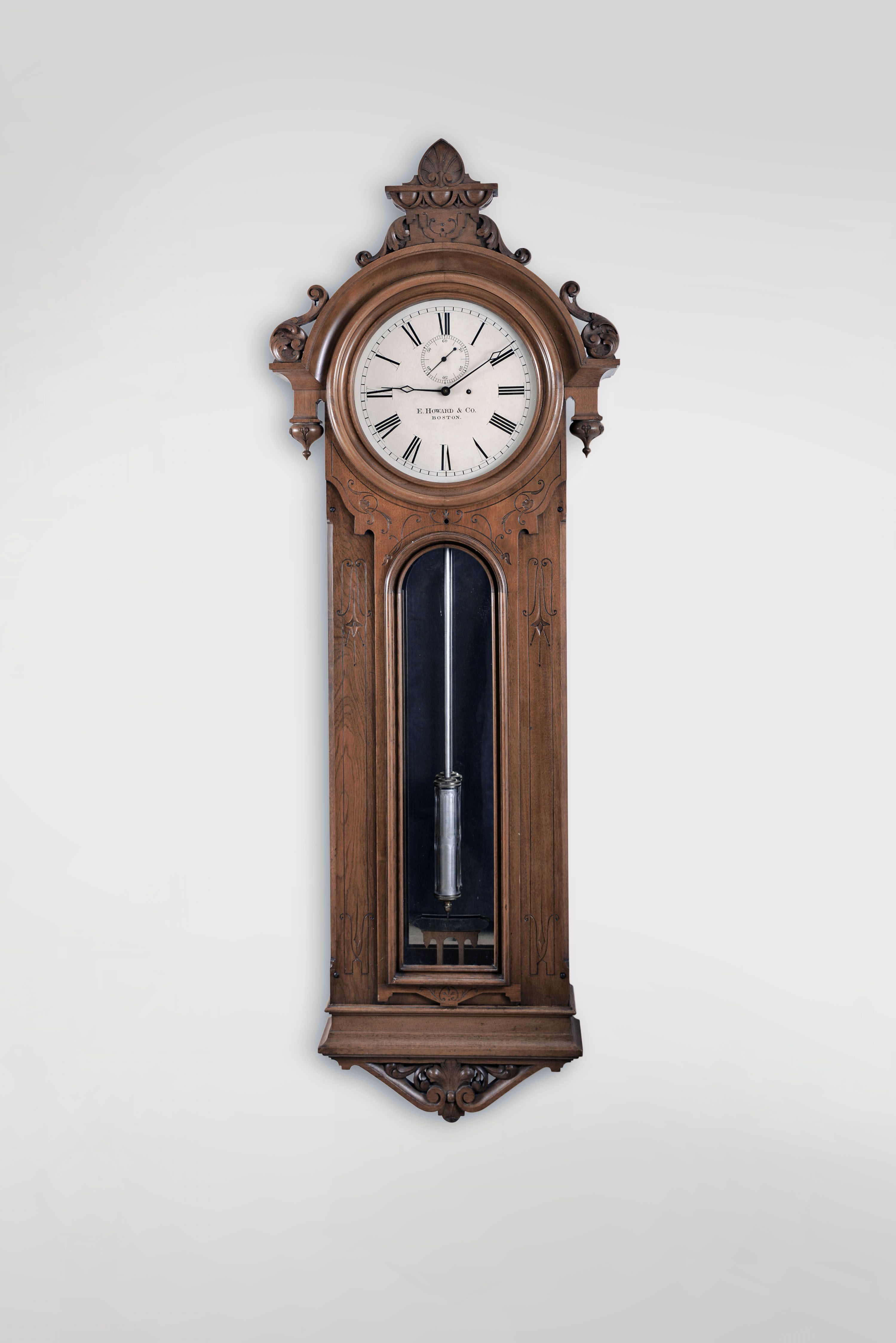 E. Howard & Co., Boston, Mass., "No. 36 Regulator", 8 day, time only, weight driven movement with Graham deadbeat escapement, meter long pendulum with loaded glass jar in a carved walnut case with mirrored back and painted metal dial. — Antique Clocks Price Guide