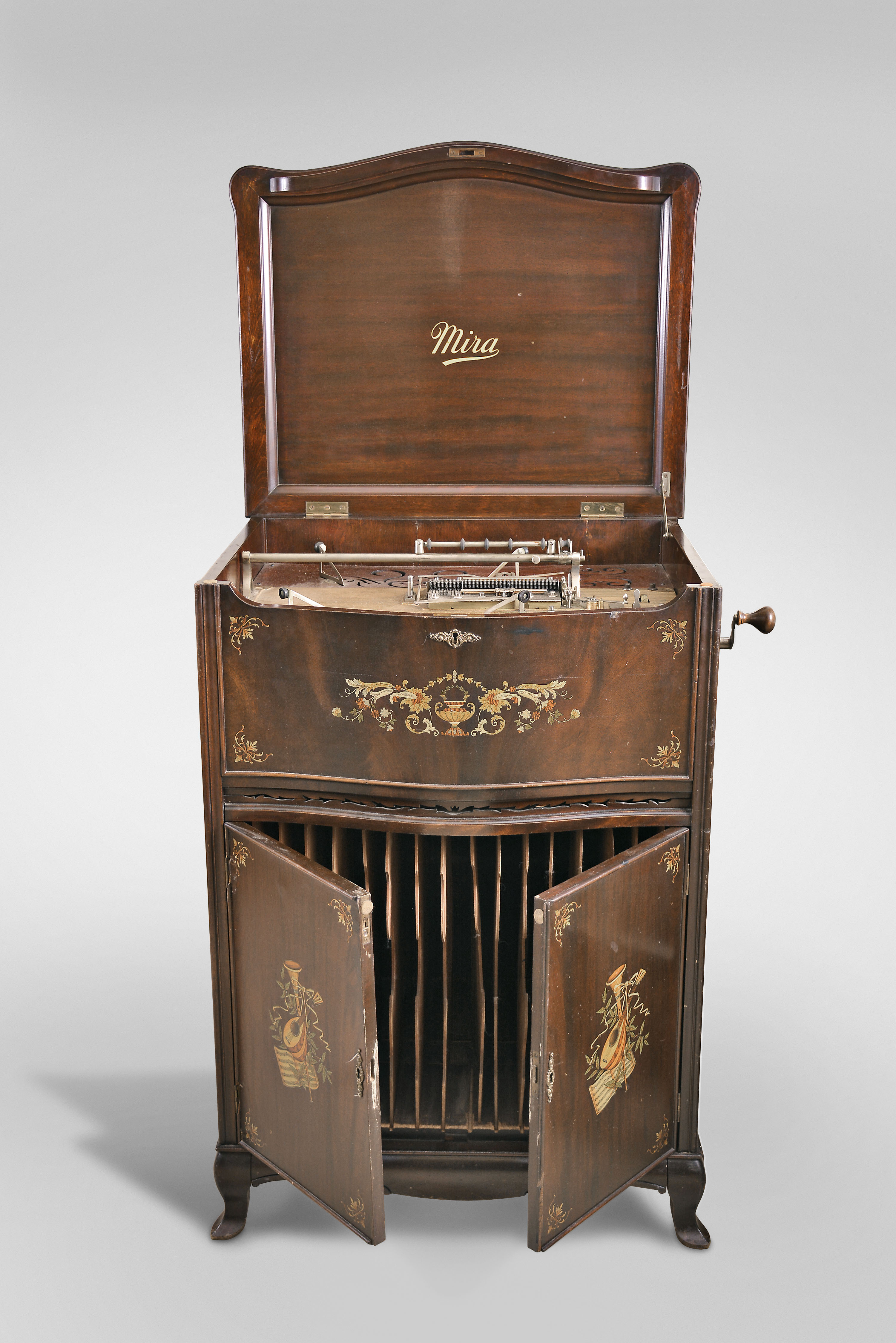 Mira Floor Standing Music Box by Mermod Freres, Ste-Croix, Switzerland, playing 18" discs on a double comb movement with two sliding dampers in a mahogany case decorated with tinted gold and silver leaf foliate transfers, with brass handles over two doors with storage for discs, all resting on slipper feet — Antique Clocks Price Guide