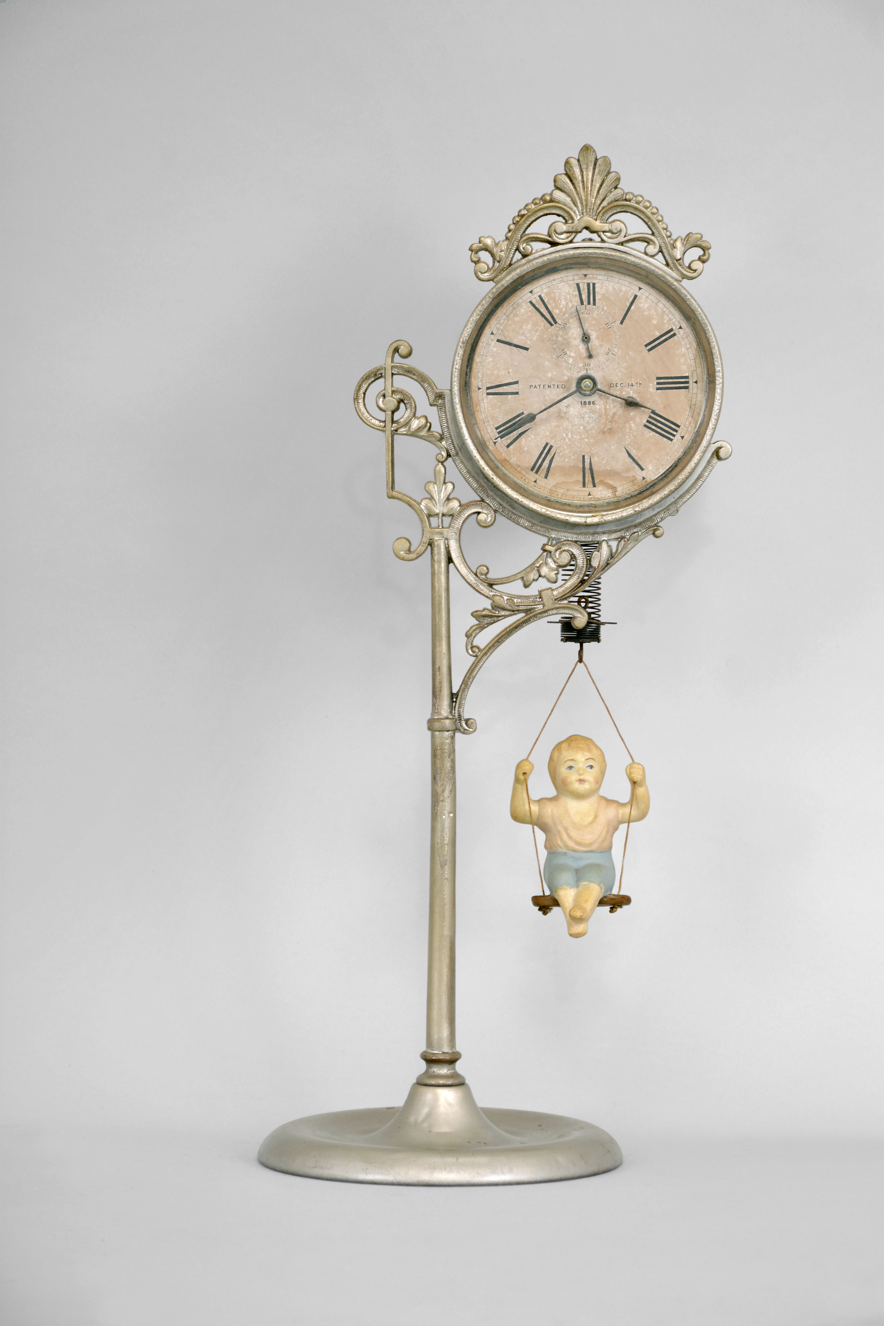 Ansonia Clock Co., New York, "Jumper No. 1" bobbing doll shelf clock with a spring driven one day timepiece movement in a nickel plated case. — Antique Clocks Price Guide