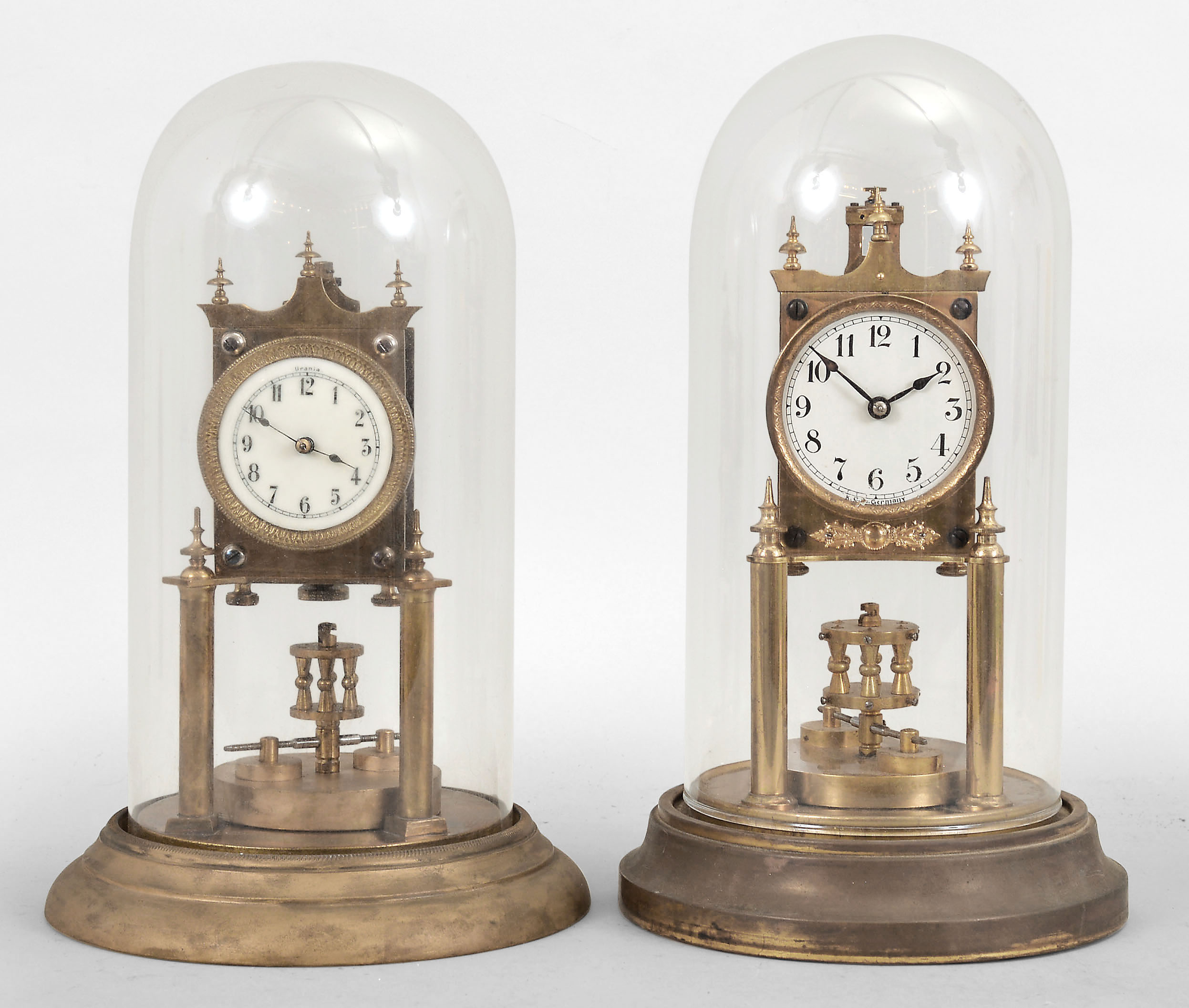 Clocks- 2 (Two) 400 day clocks: (1) Uhrenfabrik Urania Ltd., Germany, 400-day mantel clock, time only, spring driven movement with torsion disc pendulum, porcelain dial signed "Urania", under glass dome, c1908; (2) Gustav Becker, Freiberg, Germany, 400-day mantel clock, time only, spring driven movement with torsion disc pendulum, white enamel dial signed "K.C. Co. Germany", c1912. — Antique Clocks Price Guide