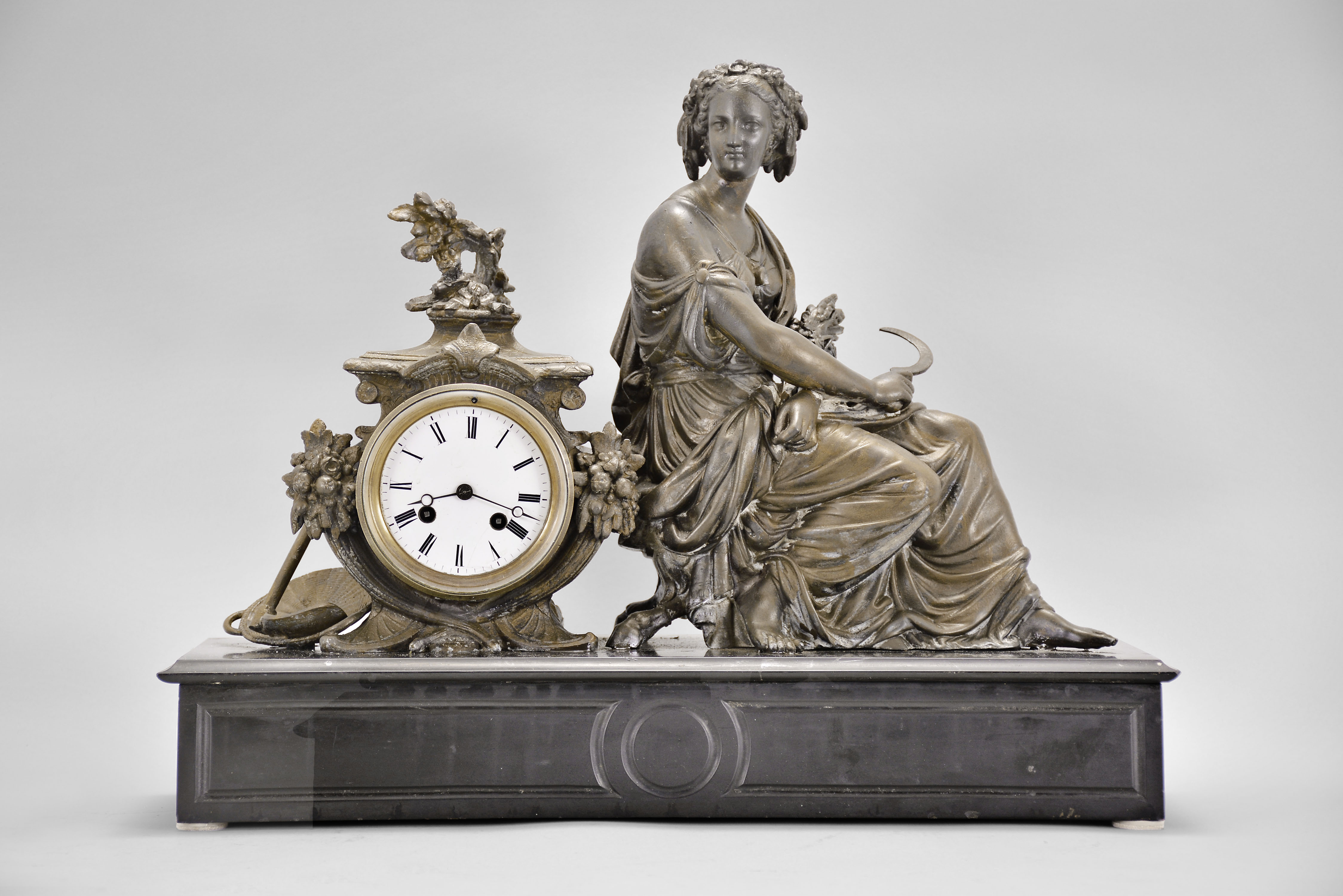 Japy Freres & Cie, Paris, France, figural mantel clock, 8 day, time and strike, spring driven pendule de Paris movement, black slate base with molded front and top supporting a cast spelter case with agrarian theme including a basket and hoe, and seated female figure with a sickle in one hand and a sheaf of wheat in the other, white enamel dial with Roman numerals, and blued steel Breguet hands. — Antique Clocks Price Guide