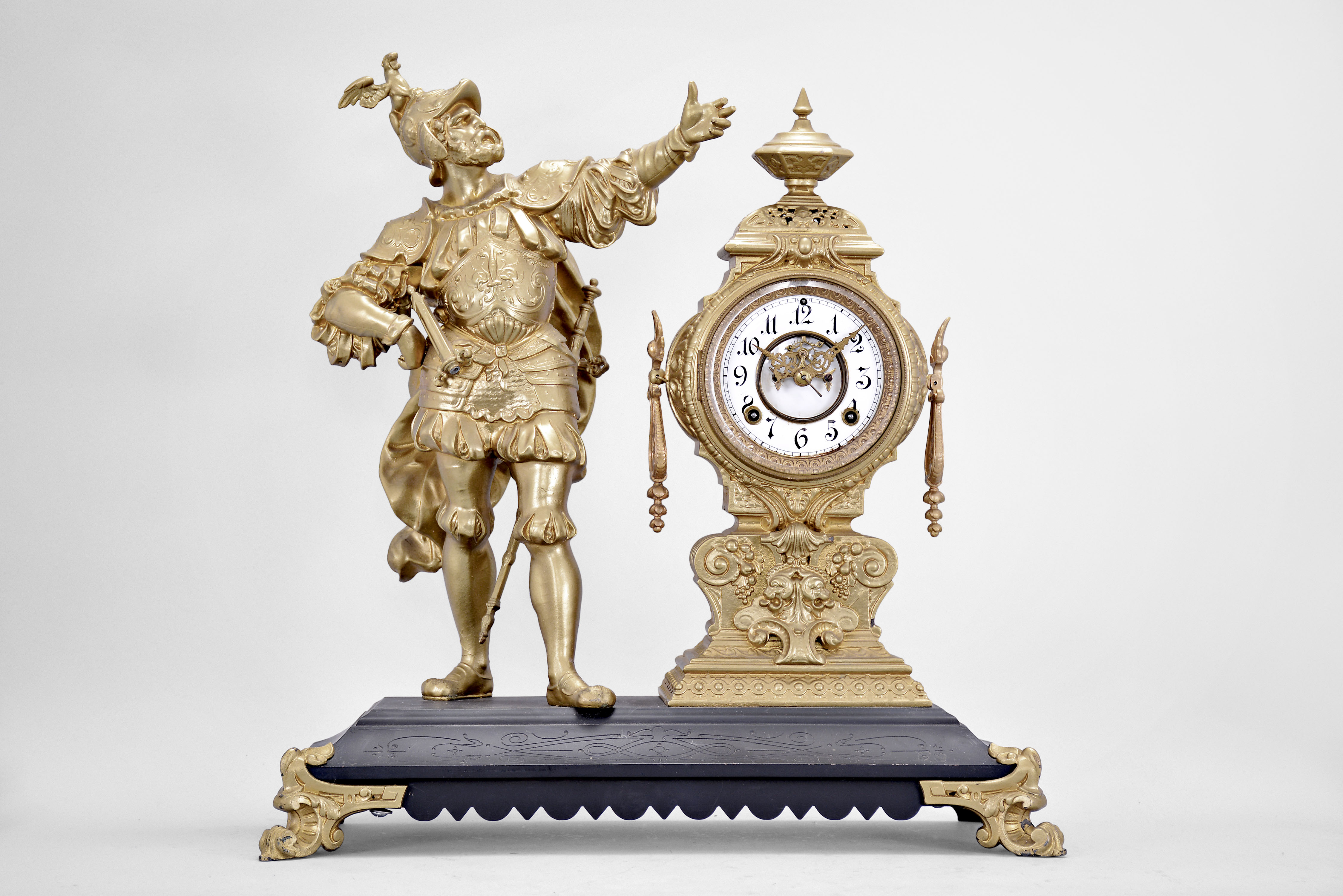 Ansonia Clock Co., New York, "Insult" figural mantel clock, 8 day, time and strike, spring driven movement with visible escapement, iron base on cast feet supporting the clock with white enamel dial and Louis XV style hands and a soldier figure with outstretched arm. — Antique Clocks Price Guide
