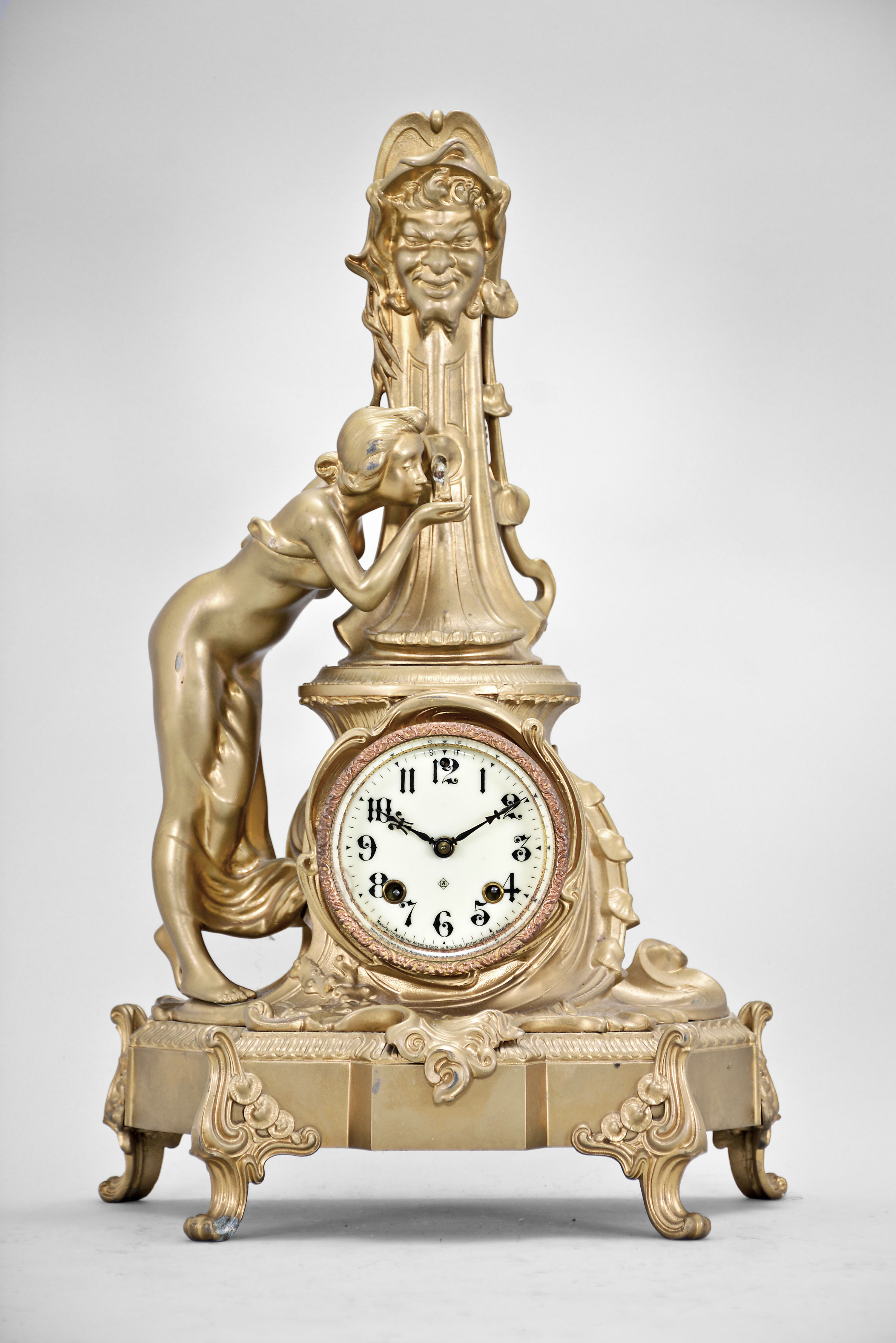 Ansonia Clock Co., New York, "Fountain" figural mantel clock, 8 day, time and strike, spring driven movement with cream porcelain dial and blued steel hands mounted within a case depicting a young woman drinking from a tall fountain. — Antique Clocks Price Guide