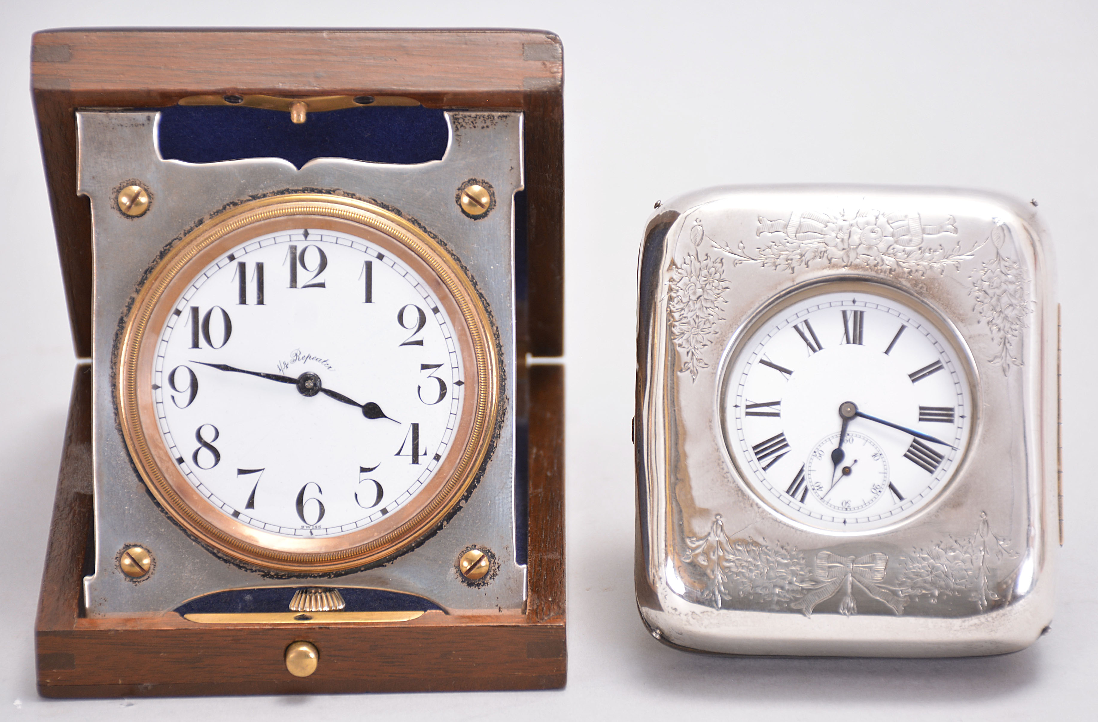 Travel clocks- 2 (Two): the first marked "Barbezat Swiss", 15 jewel, quarter repeating cotes de Geneve decorated nickel movement with arabic numeral white enamel dial, mounted to a folding sterling silver plate and hinged to a mahogany box, the top with applied foliate ornament surrounding a knight's mask and crown, above an oblong enamel panel set with a gold castle tower ornament, the other with 7 jewel Swiss movement marked "Venta", roman numeral white enamel dial, and silver open face case, contained in an easel back, leather clad, velvet lined box, the front mounted with sterling silver and engraved with floral drops, garlands, and bow knots, with London hallmark, and date letter for the year 1908 — Antique Clocks Price Guide