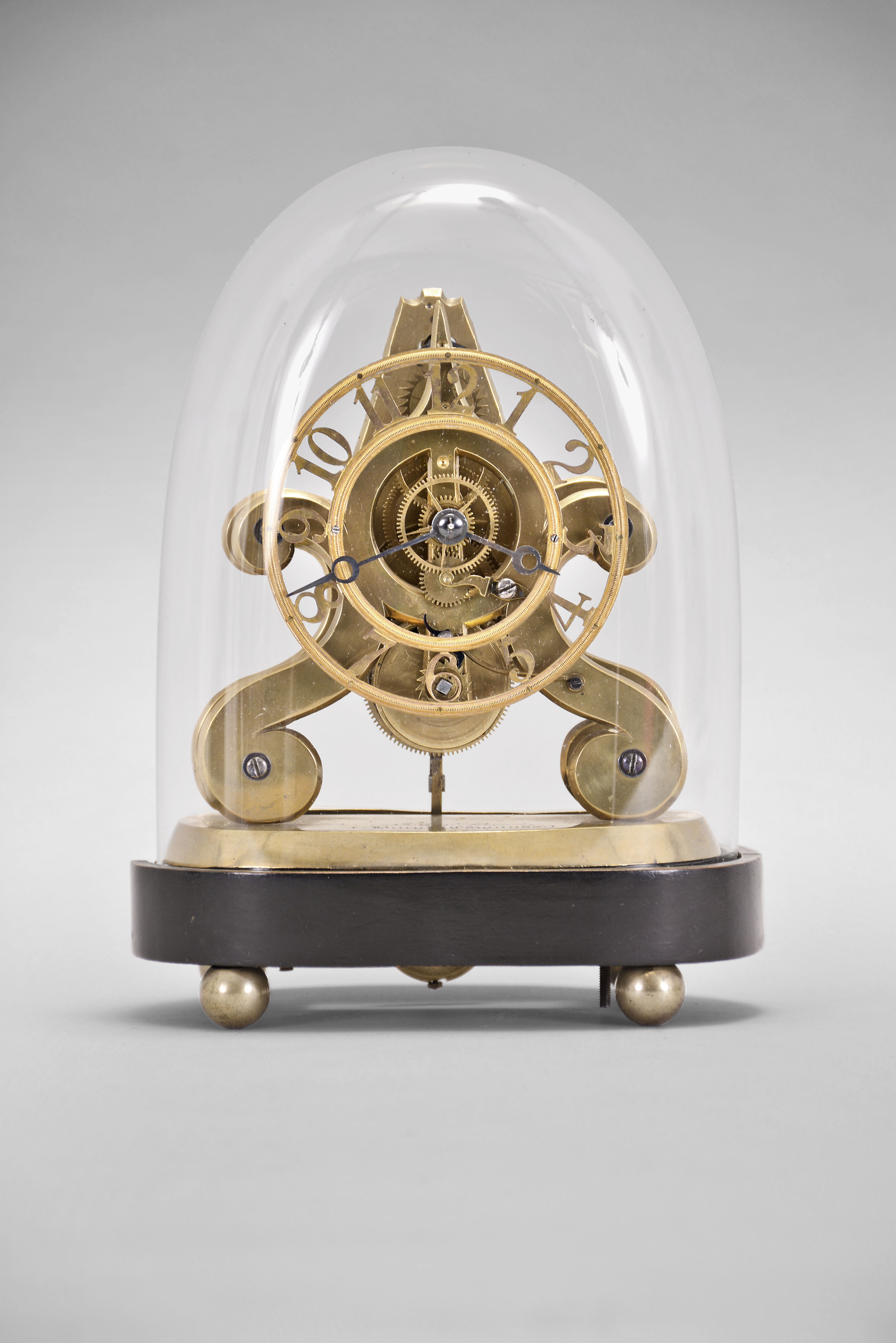 John Pace, Bury, St. Edmunds, a rare miniature skeleton timepiece, the brass scroll frames and brass base with beveled edges, the back plate measuring just 5 1/4" in height, 8 day fusee movement with thread suspension and recoil escapement and light wheels with five spoke crossings, skeletonized, Arabic numeral dial with knurled inner and outer rings, blued steel Breguet style hands, all resting on an ebonized oval base with brass ball feet and conforming dome. Brass base signed "John Pace Bury St. Edmunds 229 " — Antique Clocks Price Guide