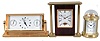 Clocks- 3 (Three) Fancy Modern Desk: (1) Mathew Norman, Switzerland, carriage clock, 8 day, time only, spring driven movement with visible balance wheel movement in a highly polished brass case with beveled glass sides and dome top; (2) Chelsea Clock Co., Boston, quartz clock with thermometer and hygrometer in polished brass case; (3) Linden, North Smithfield, RI, quartz table clock in a wood and metal case.