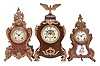 Clocks- 3 (Two) Ansonia Clock Co., New York, 8 day, time and strike, spring driven movements, porcelain dials: (1) "Apollo" mantel clock finished in red with gilt trimmings, c1901; (2) "Triano" mantel clock mantel clock with purple painted porcelain panel, c1901; (3) Mantel clock in a wood case with applied cast ornaments and eagle finial, c1890.