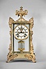 Ansonia Clock Co., New York, "Marchioness" crystal regulator with a spring driven 8 day time and half hour strike (rack and snail) movement (visible escapement) in a polished brass case with rich gold ornaments.