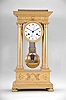 Boileau a Paris, an early 19th century, half seconds beating gilt bronze portico clock, on floral medallion ornamented compressed ball feet, base molding decorated with palmette, anthemion and bellflower, the dado with mount having a central sunflower with mask, and flanking Grecian foliate ornament below the simple molded surbase, four columns with square plinths, laurel wreathed molded bases, and egg and dart capitals supporting the entablature, the frieze with floral medallions and cornice with waterleaf, palmette and bellflower, laurel wreath bezel with simple foliate inner ring, roman numeral white enamel dial with inner seconds chapter,signed "Boileau a Paris", blued steel Breguet style hands and central seconds hand, large two train movement with knife edge suspension and pin wheel escapement, counting the hours on a bell, and heavy bimetallic half seconds beating gridiron pendulum