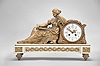 France, figural mantel clock, 8 day, time and strike, spring driven pendule de Paris movement in a cast metal case mounted on a white marble base with cast gilt feet and applied ornaments, the clock with white enamel dial, polychrome garlands, and Louis XV style hands, all adjacent to the figure of a seated woman reading a book.