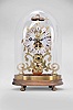 Whytock and Sons, Dundee, a mid 19th century skeleton clock with passing strike, the frames fretted in the form of vines and foliage topped with a finely finished bell, the fusee movement with recoil escapement and inline wheelwork with five spoke crossings confined to the center of the frame and so allowing for a very open design, the silvered dial with gothic roman numerals also following the frame design, and incorporating thistle, vine and shamrock motifs, fancy blued steel hands and heavy brass clad pendulum, beneath an oval glass dome with conforming wooden base