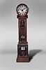 James Arthur, New York, an unusual drumhead regulator made as a wedding gift for his daughter, Bessie Humphrey Arthur, the mahogany case with glazed base and trunk, the glasses surrounded by half round moldings with decorative brass nails, and with applied, cast brass ornaments, decorative latches and hinges, the signed and dated timepiece movement with damascened, skeletonized brass plates and boxwood wheels, and visible through the trunk door, a bevel geared linkage extending into the drumhead top and driving the motion work, the seatboard with engraved presentation plaque, "Bessie Humphrey Arthur from her father James Arthur October 25th 1904", the movement driven by two reeded brass weights, with heavy brass disc pendulum decorated with turned, concentric beads, and the two piece wooden rod with beat adjustment device, all components reflected in the mirrored case back, silvered dial with pierced arabic numerals and minute markers, and blued steel hands of Arthur's design, together with a copy of Hering's "The Lure of the Clock", which documents the Arthur collection and his thoughts on clockmaking.