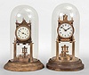 Clocks- 2 (Two) 400 day clocks: (1) Uhrenfabrik Urania Ltd., Germany, 400-day mantel clock, time only, spring driven movement with torsion disc pendulum, porcelain dial signed "Urania", under glass dome, c1908; (2) Gustav Becker, Freiberg, Germany, 400-day mantel clock, time only, spring driven movement with torsion disc pendulum, white enamel dial signed "K.C. Co. Germany", c1912.