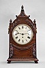 England, a 19th century mahogany bracket clock with passing strike, the case on turned wooden feet, the base with quarter round, and bead and reel moldings below a carved festoon, the upper part of the case with two carved laurel fronds, turned, carved finials, and pagoda top with carved, partial C scrolls and bellflower, the sides with pierced brass, lancet arch frets, and stamped, ring handles with floral mounts, roman numeral white painted dial with blued steel Breguet style hands, 8 day fusee timepiece with shouldered plates, recoil escapement, and passing strike at the hour, brass pendulum with brass clad bob