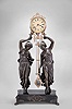Ansonia Clock Co., New York, "Double Figure Swing" mystery clock, 8 day, time only, spring driven movement in a nickel plated cylindrical case with cast ribbon ornament, held aloft by a pair of spelter figures standing on a black enamel base with paw feet.