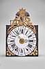 France, Louis XV Comtoise clock, 8 day, time and strike with alarm, weight driven movement with verge escapement, thread suspension with rear-hanging pendulum, iron post and plate frame, dial composed of 13 enamel panels with Roman and Arabic numerals, brass alarm ring with Arabic numerals, two pierced brass hands, cast brass spandrels below the dial with putti supporting crowns, all topped by a cast brass fronton with sun emblem within a rococo design.