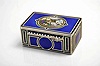 Karl Griesbaum, Germany, an enamelled silver singing bird box, the case with rectilinear panels decorated in blue, black, green and white enamels, the top in blue guilloche enamel with narrow black enamel border, the oval cover decorated with polychrome enamel flowers, and with green and black enamel border, opening to reveal a small, colorful bird, performing a short song and dance prior to disappearing beneath the cover, with key.