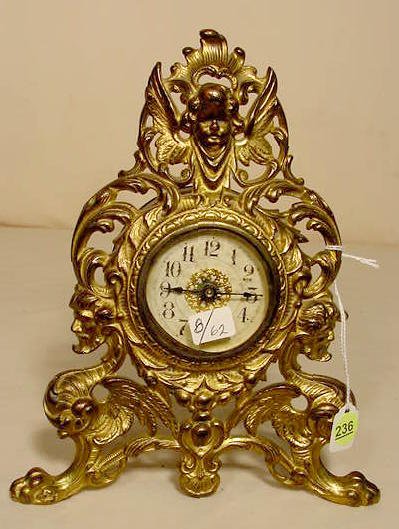 Figural cherub & man/dragon metal desk clock: — Antique Clocks Price Guide